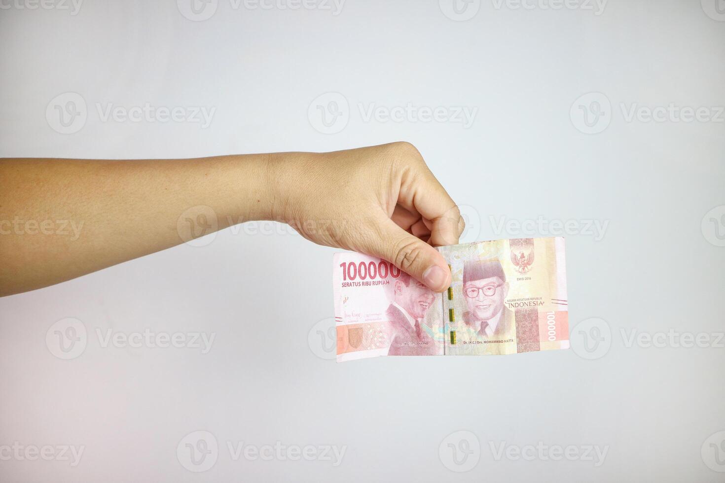 Hands giving out one hundred thousand money on white background, rupiah money 100000 photo
