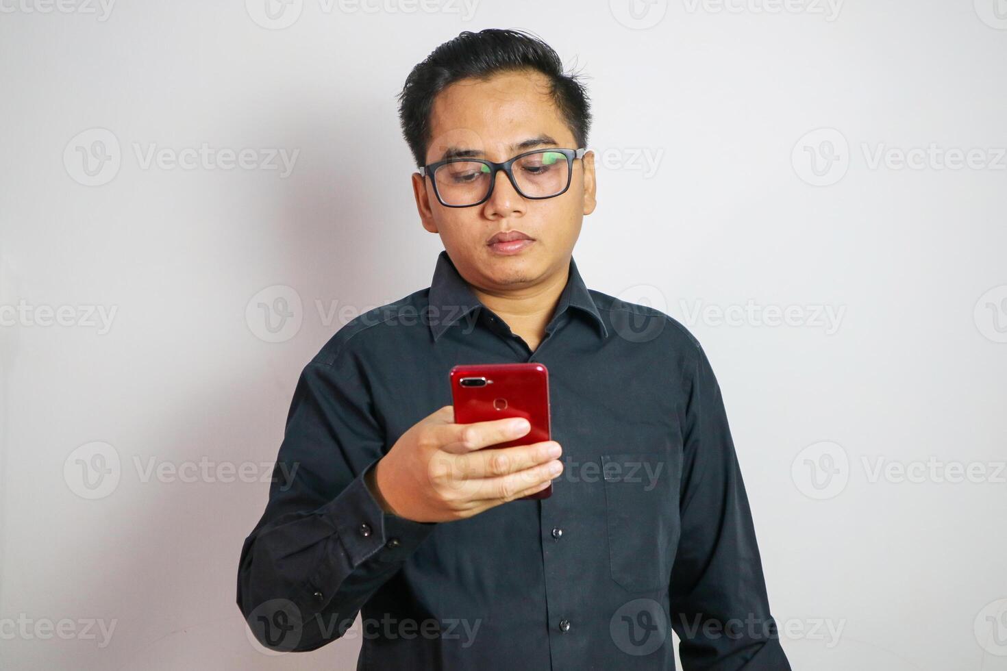 Asian man seriously concentrated on smartphone isolated on white background. photo