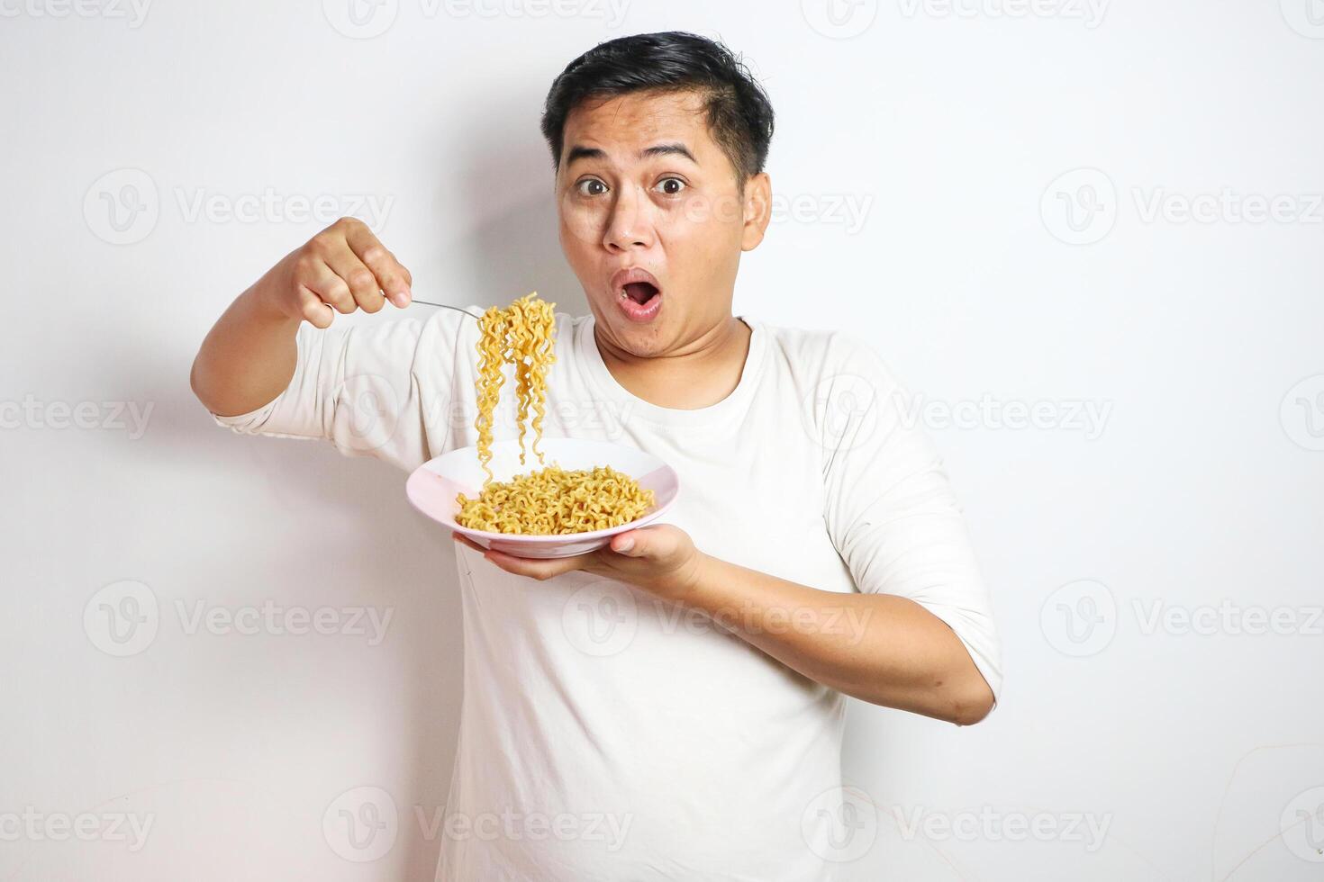 Adult Asian man showing surprised expression while eating noodle photo
