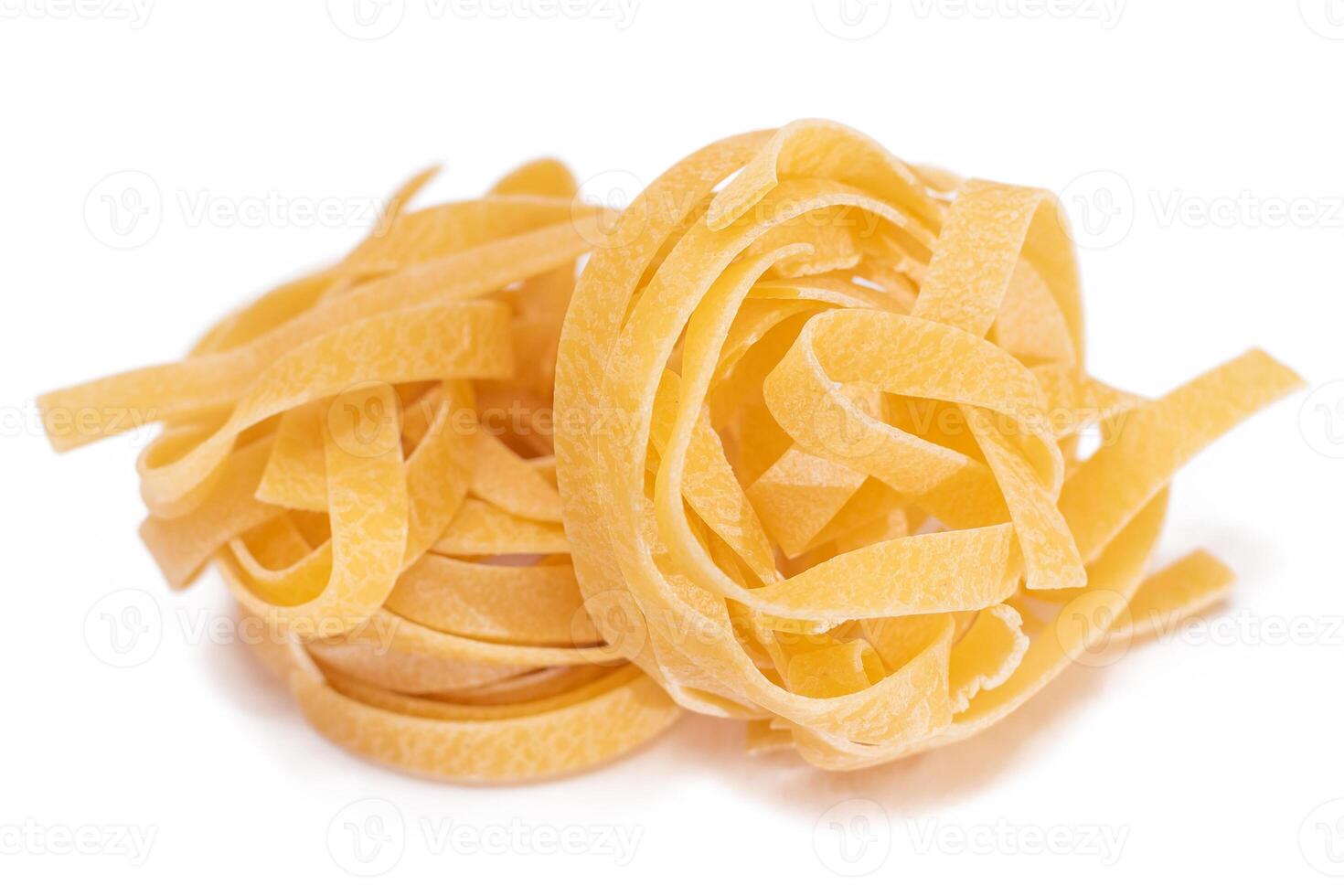 Two Classic Italian Raw Egg Fettuccine - Isolated on White Background. Dry Twisted Uncooked Pasta. Italian Culture and Cuisine. Raw Golden Macaroni Pattern - Isolation photo
