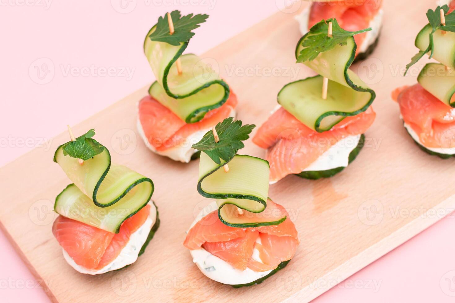 Canapes without Bread with Fresh Salmon, Cucumber and Cream Cheese on Wooden Cutting Board. Easy Breakfast. Diet Food. Quick and Healthy Sandwiches. Healthy Snacks with Tasty Fillings photo