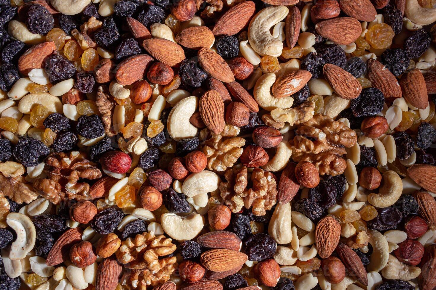 Mixed Nuts. Almonds, Walnuts, Cashews, Peanuts, Hazelnuts, Dried Prunes and Raisins. Different Nut Mix. Background from Various Nuts and Dried Fruits photo