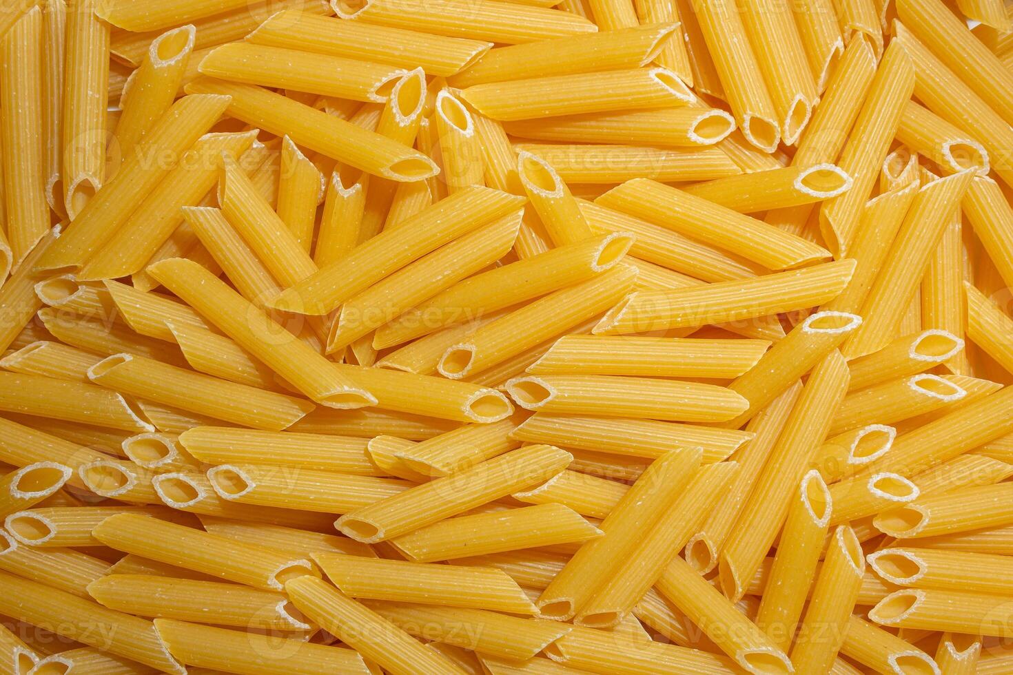 Uncooked Penne Rigate Pasta. A Culinary Canvas of Penne Macaroni, Creating a Lively and Textured Background for Gourmet Cooking. Dry Pasta. Raw Macaroni - Top View, Flat Lay photo