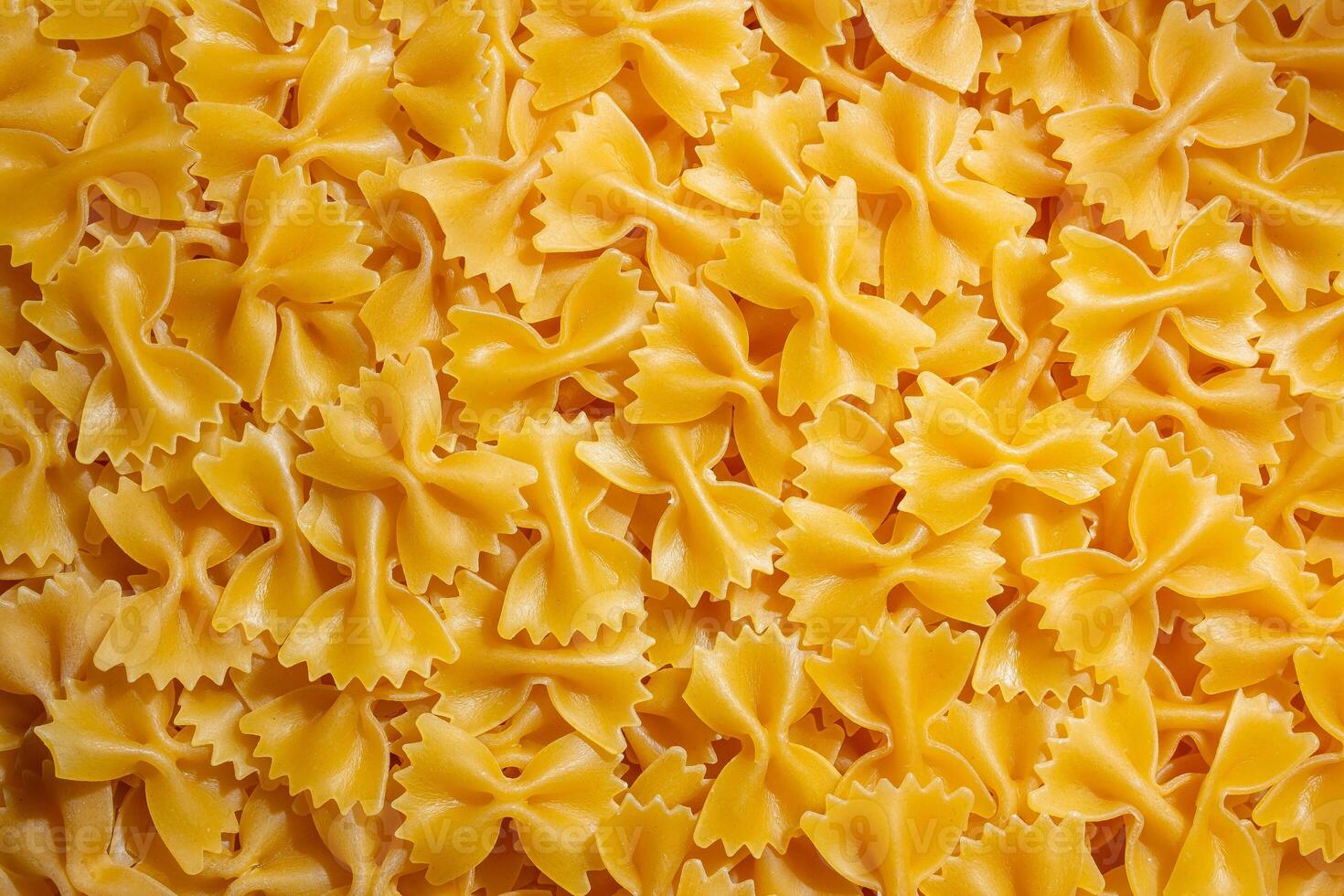 Uncooked Farfalle Pasta. A Culinary Canvas of Bow-Tie Macaroni, Creating a Lively and Textured Background for Gourmet Cooking. Dry Pasta. Raw Macaroni - Top View, Flat Lay photo