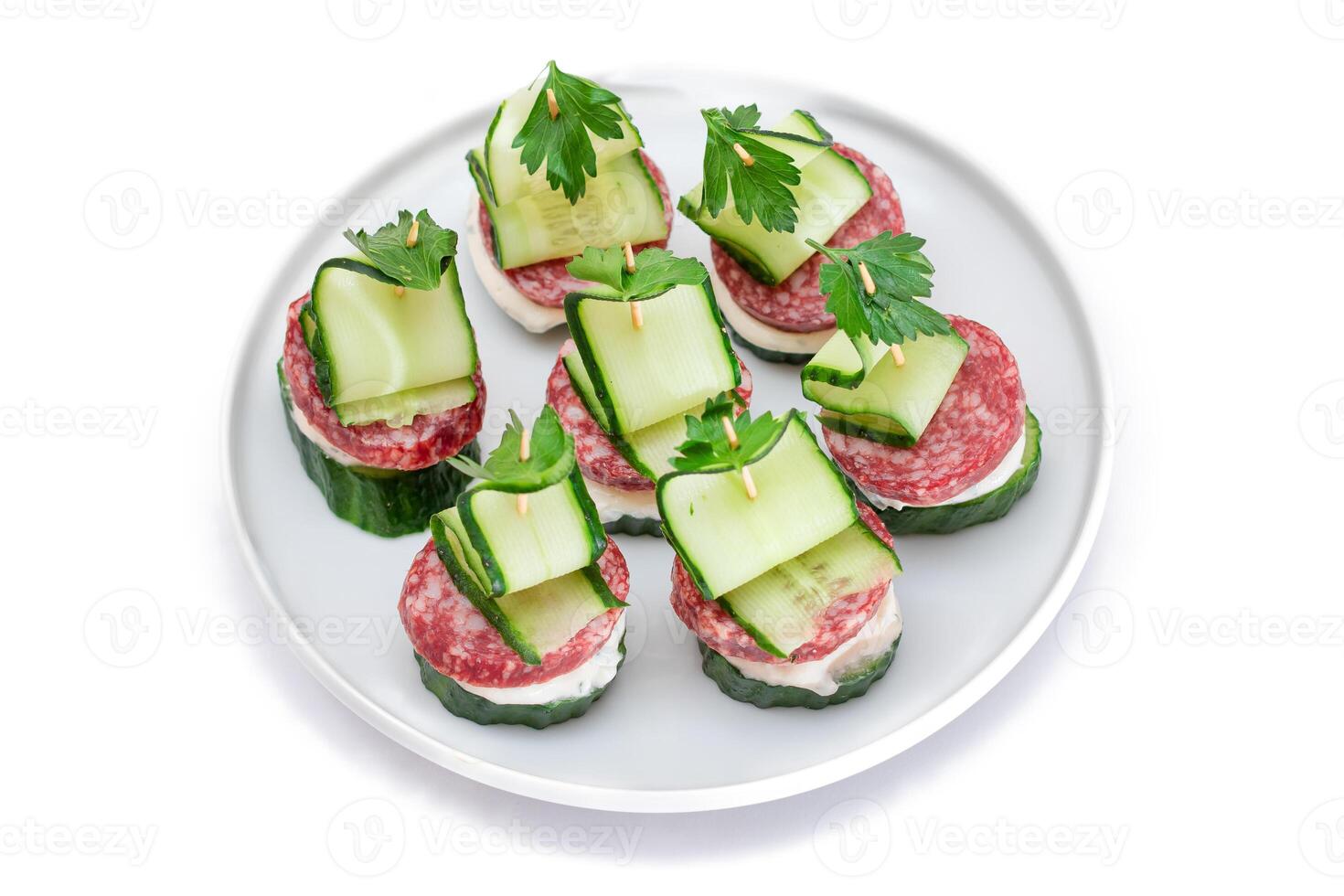 Canapes without Bread with Salami, Cucumber, Greens and Cream Cheese on White Plate - Isolated on White. Easy Breakfast. Diet Food. Quick and Healthy Sandwiches. Healthy Snacks with Tasty Fillings photo