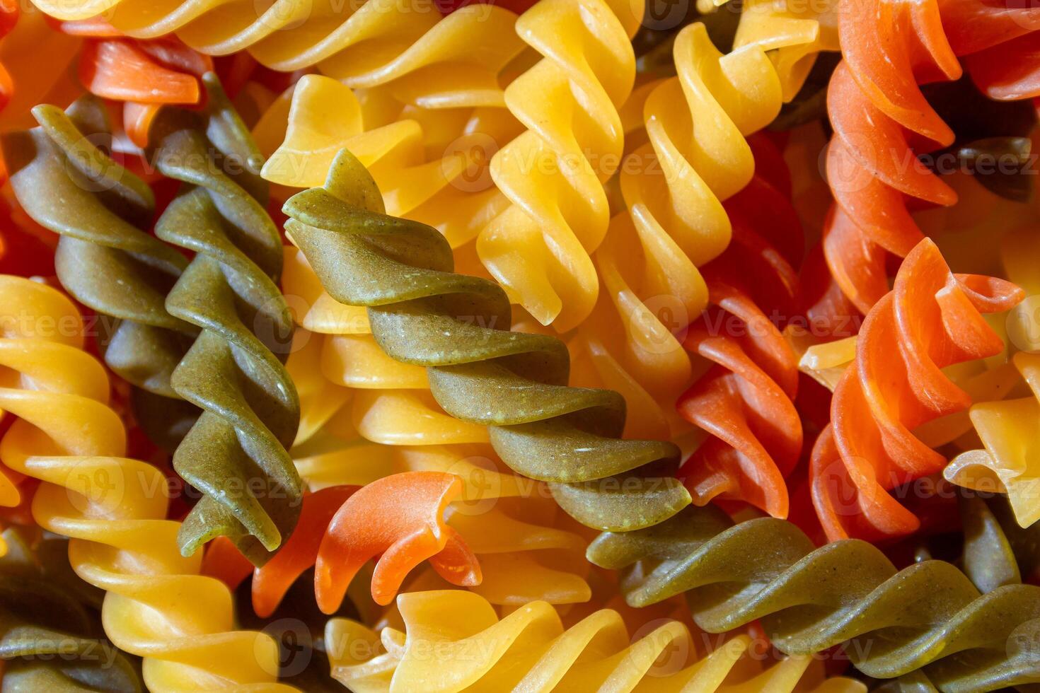 Uncooked Vibrant Colored Fusilli Pasta. A Mesmerizing Culinary Canvas of Multicolored Spirals, Creating a Lively and Textured Background for Gourmet Cooking. Colored Dry Pasta. Raw Macaroni photo