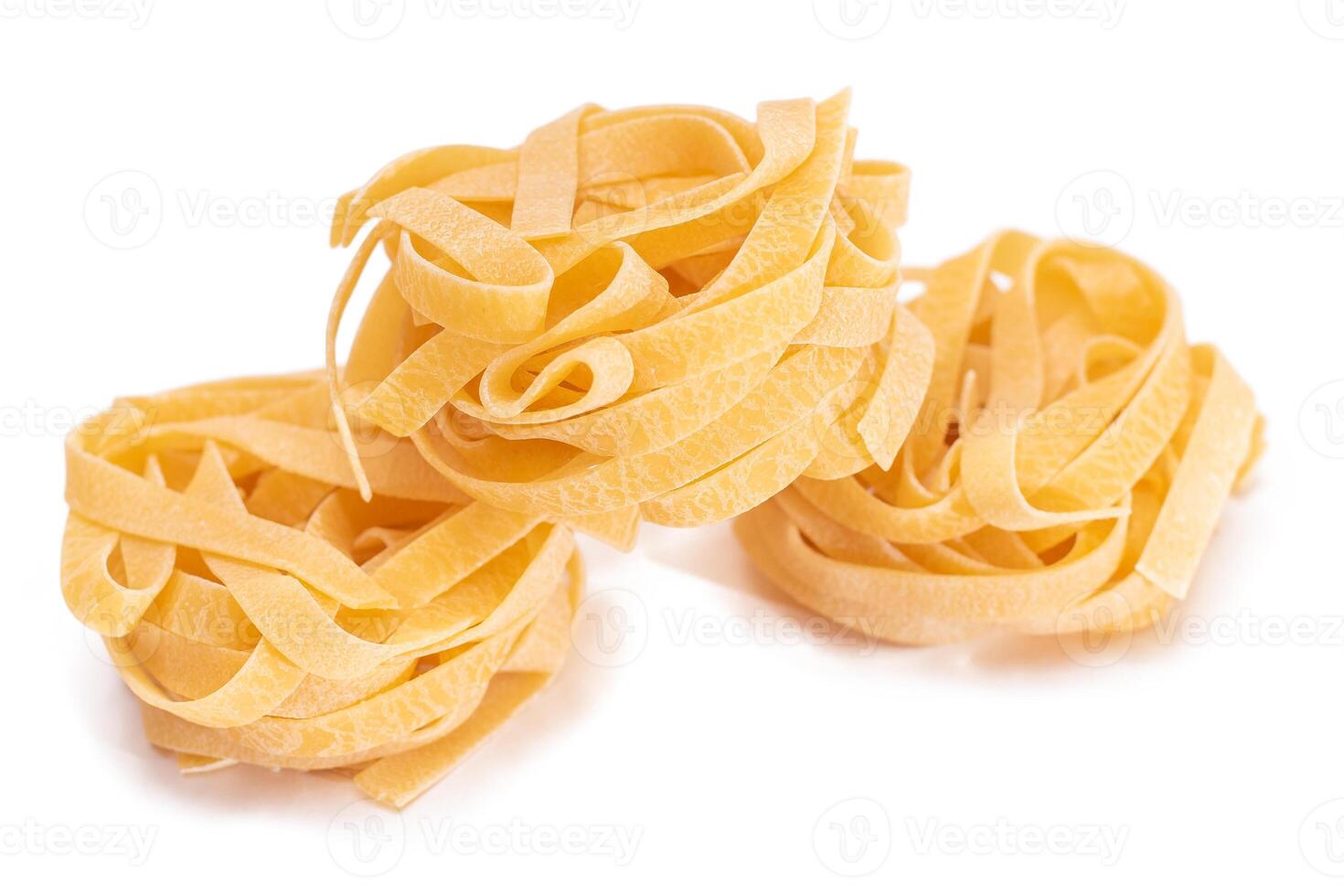 Three Classic Italian Raw Egg Fettuccine - Isolated on White Background. Dry Twisted Uncooked Pasta. Italian Culture and Cuisine. Raw Golden Macaroni Pattern - Isolation photo