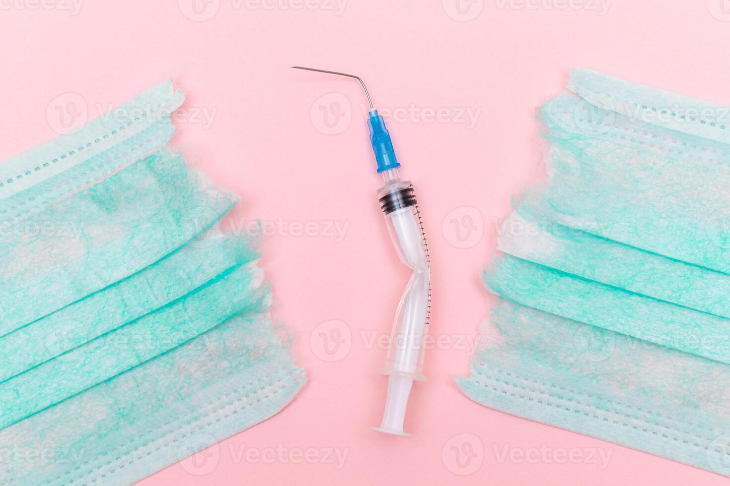 Anti Vaccine Movement and Anti Mask Concept - Broken Medical Syringe and Green Torn Medical Face Mask on the Pink Background. Pandemic and Lockdown End - Top View, Flat Lay photo