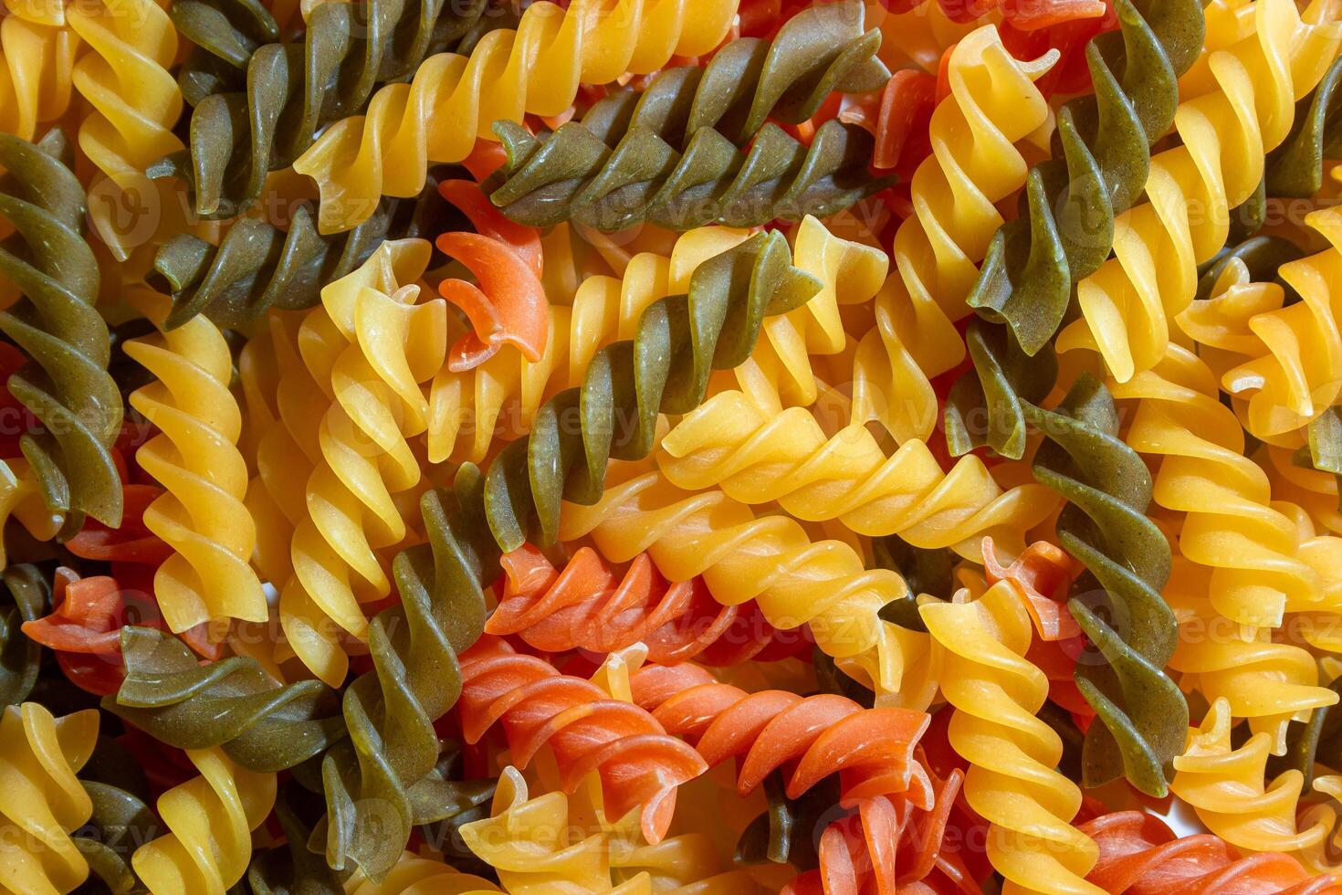 Uncooked Vibrant Colored Fusilli Pasta. A Mesmerizing Culinary Canvas of Multicolored Spirals, Creating a Lively and Textured Background for Gourmet Cooking. Colored Dry Pasta. Raw Macaroni photo
