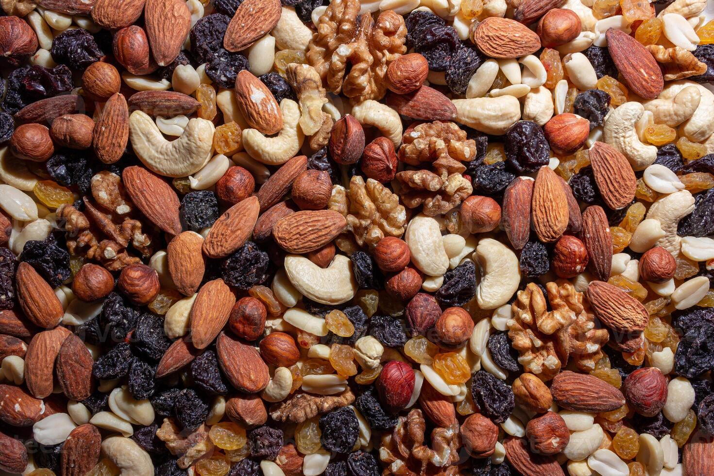 Mixed Nuts. Almonds, Walnuts, Cashews, Peanuts, Hazelnuts, Dried Prunes and Raisins. Different Nut Mix. Background from Various Nuts and Dried Fruits photo