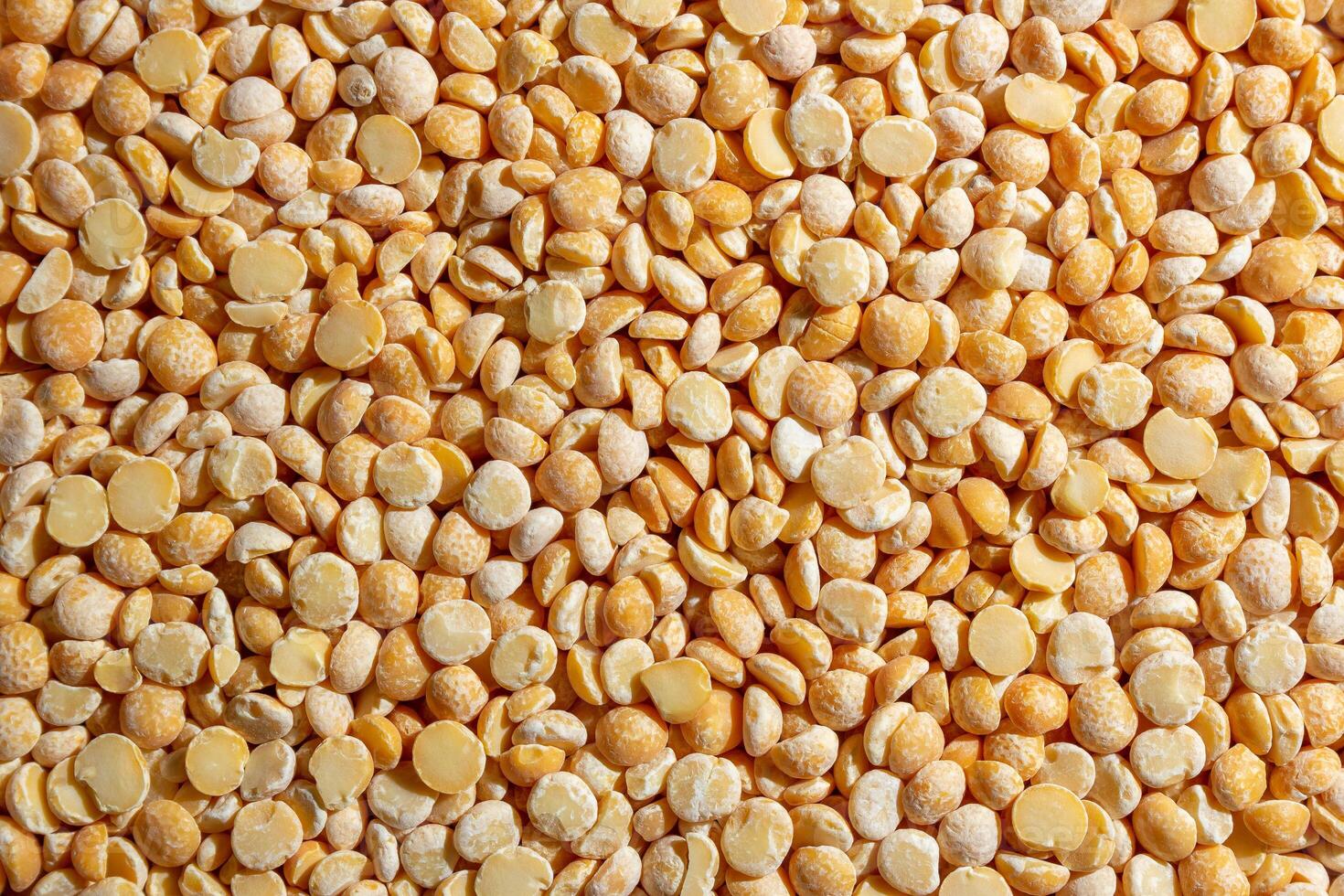 Uncooked Polished Split Peas Background. A Culinary Canvas of Dry Yellow Peas, Creating a Lively and Textured Background for Gourmet Cooking. Scattered Raw Polished Peas. Healthy Eating Ingredients photo