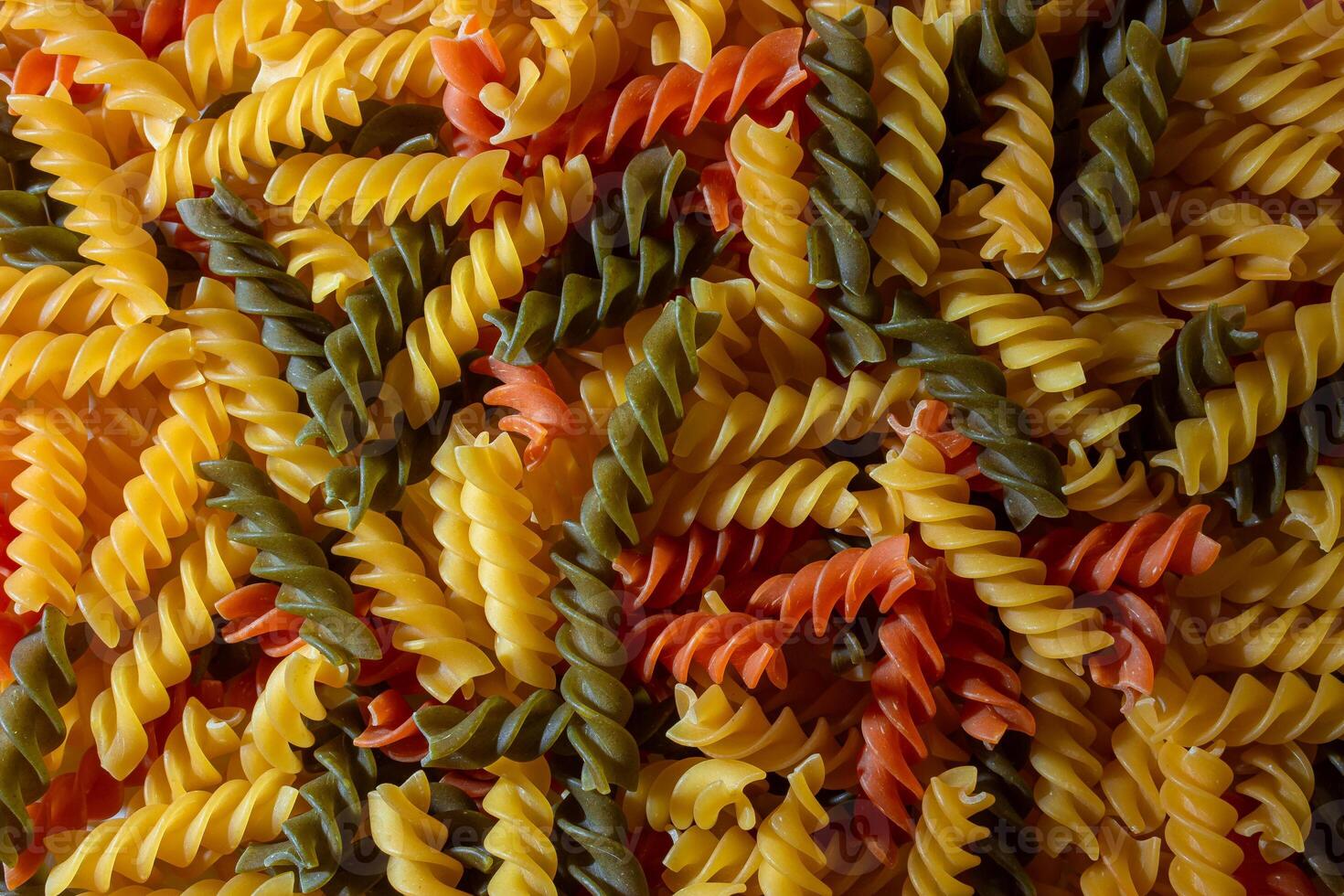 Uncooked Vibrant Colored Fusilli Pasta. A Mesmerizing Culinary Canvas of Multicolored Spirals, Creating a Lively and Textured Background for Gourmet Cooking. Colored Dry Pasta. Raw Macaroni photo