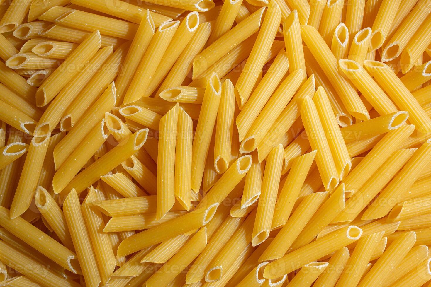 Uncooked Penne Rigate Pasta. A Culinary Canvas of Penne Macaroni, Creating a Lively and Textured Background for Gourmet Cooking. Dry Pasta. Raw Macaroni - Top View, Flat Lay photo