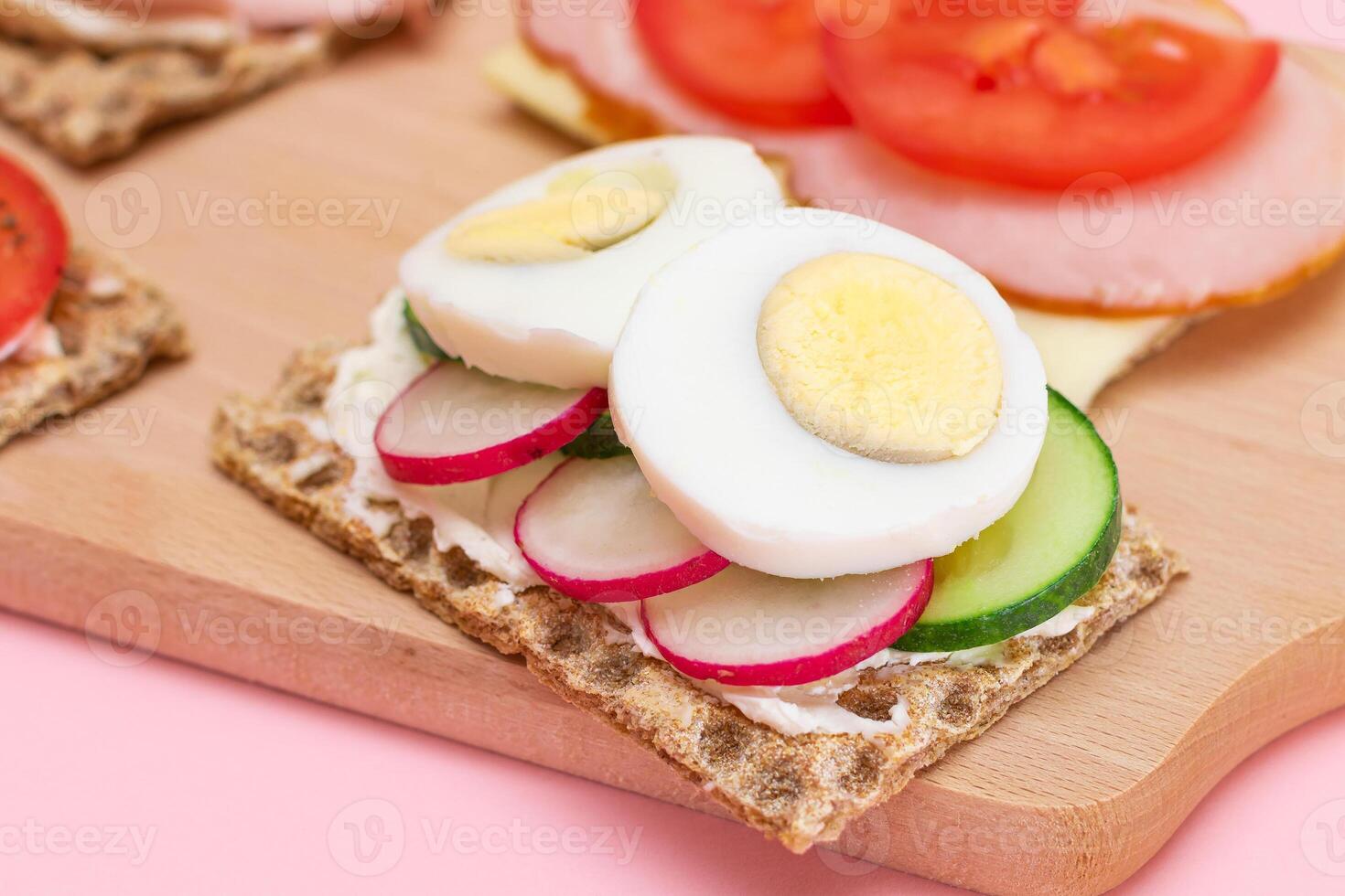Different Whole Grain Crispbread with Ham, Tomato, Radish, Cucumber and Cheese. Easy Breakfast. Diet Food. Quick and Healthy Sandwiches. Crispbread with Tasty Filling. Healthy Dietary Snack photo