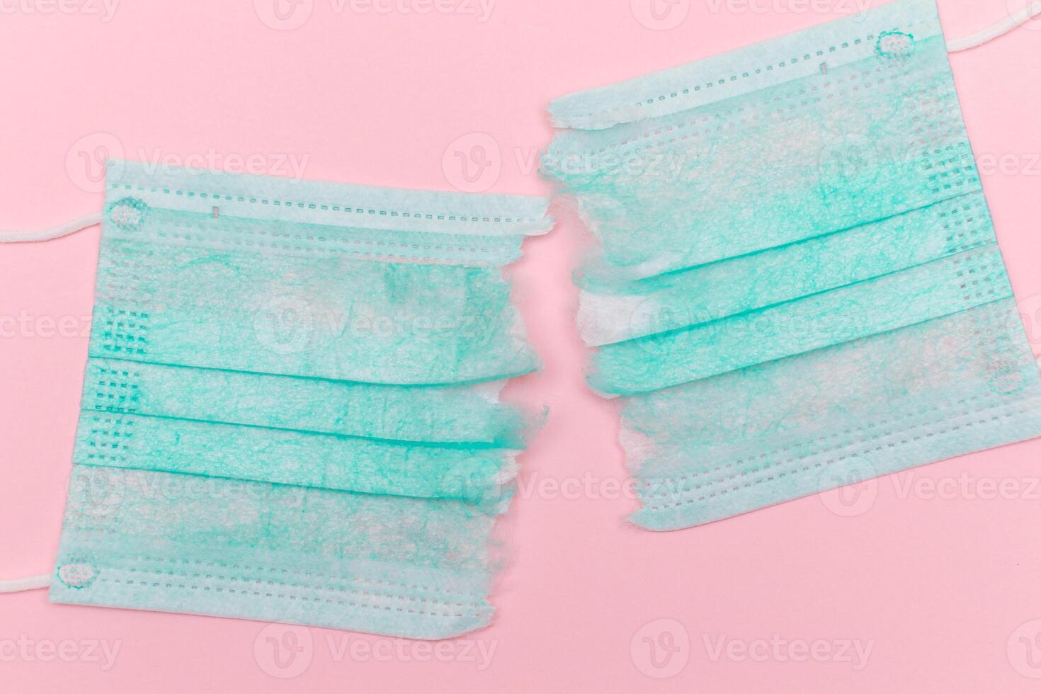 Anti Mask Movement - Green Torn Medical Face Mask on the Pink Background. Pandemic and Lockdown End - Top View, Flat Lay photo