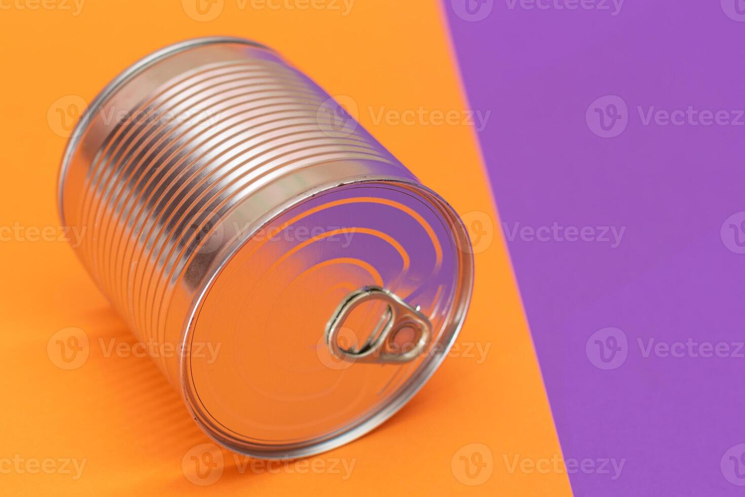 Unopened Tin Can on Split Orange and Violet Background. Canned Food. Aluminum Can for Safe and Long Term Storage of Food. Steel Sealed Food Storage Container photo