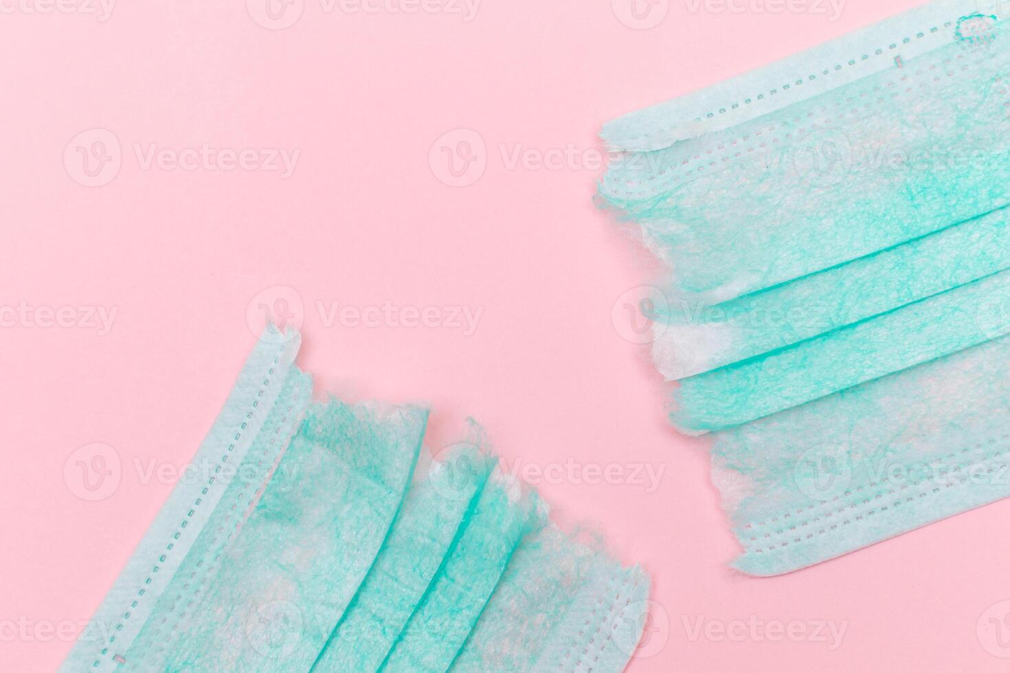 Anti Mask Movement - Green Torn Medical Face Mask on the Pink Background. Pandemic and Lockdown End - Top View, Flat Lay photo