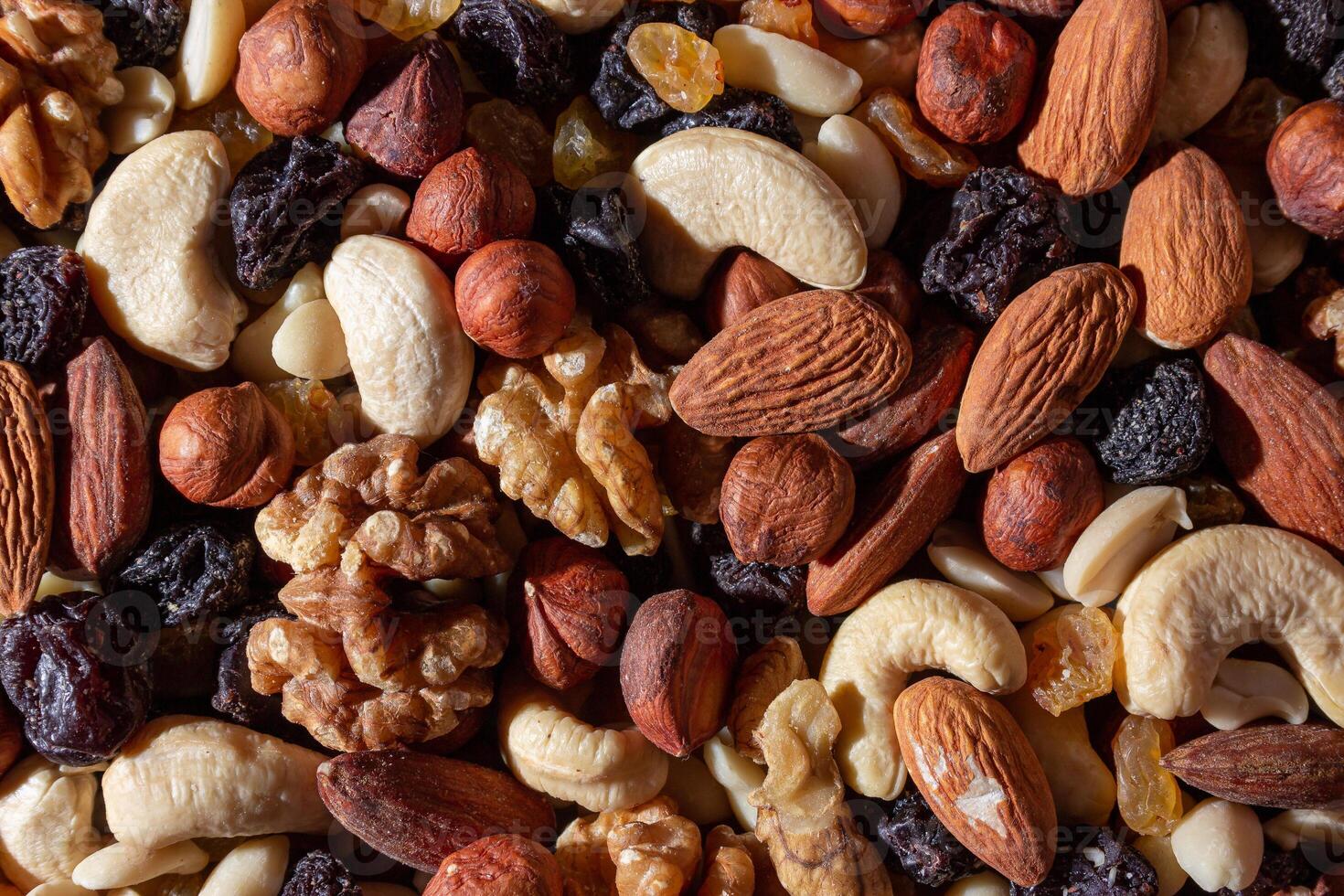 Mixed Nuts. Almonds, Walnuts, Cashews, Peanuts, Hazelnuts, Dried Prunes and Raisins. Different Nut Mix. Background from Various Nuts and Dried Fruits photo