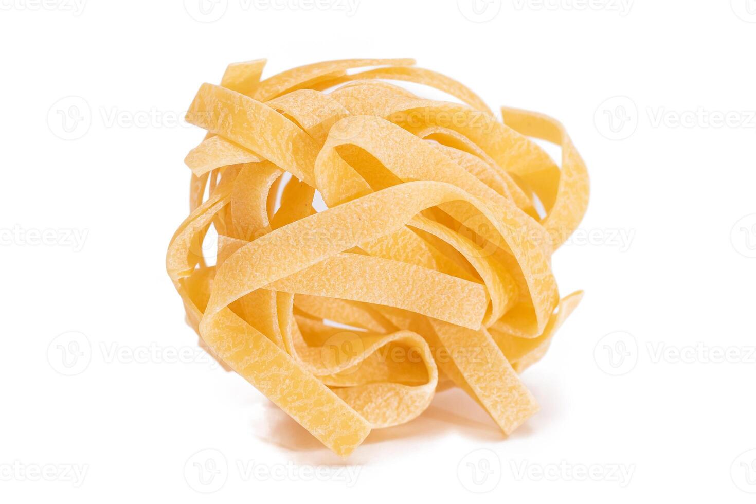 One Classic Italian Raw Egg Fettuccine - Isolated on White Background. Dry Twisted Uncooked Pasta. Italian Culture and Cuisine. Raw Golden Macaroni Pattern - Isolation photo