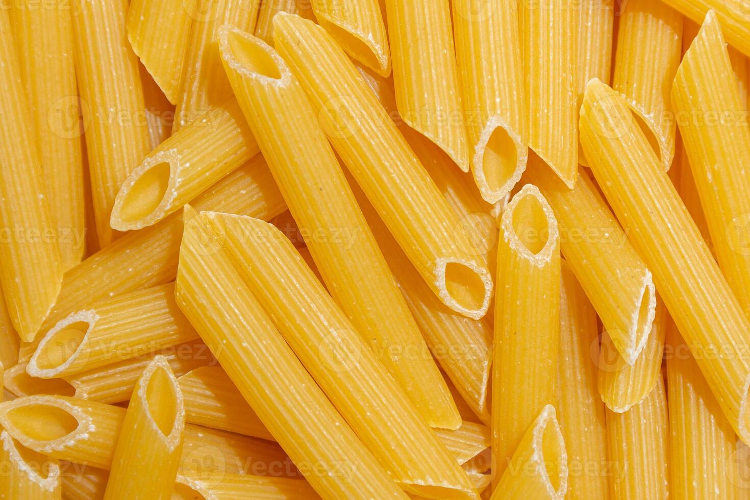 Uncooked Penne Rigate Pasta. A Culinary Canvas of Penne Macaroni, Creating a Lively and Textured Background for Gourmet Cooking. Dry Pasta. Raw Macaroni - Top View, Flat Lay photo