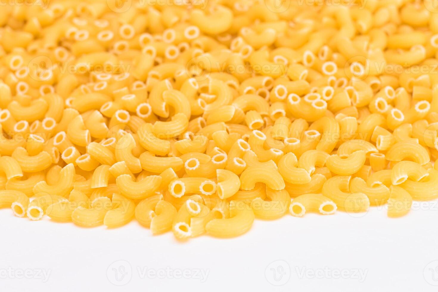 A Heap of Uncooked Chifferi Rigati Pasta on White Background. Fat and Unhealthy Food. Classic Dry Macaroni Texture. Italian Culture and Cuisine. Raw Pasta photo