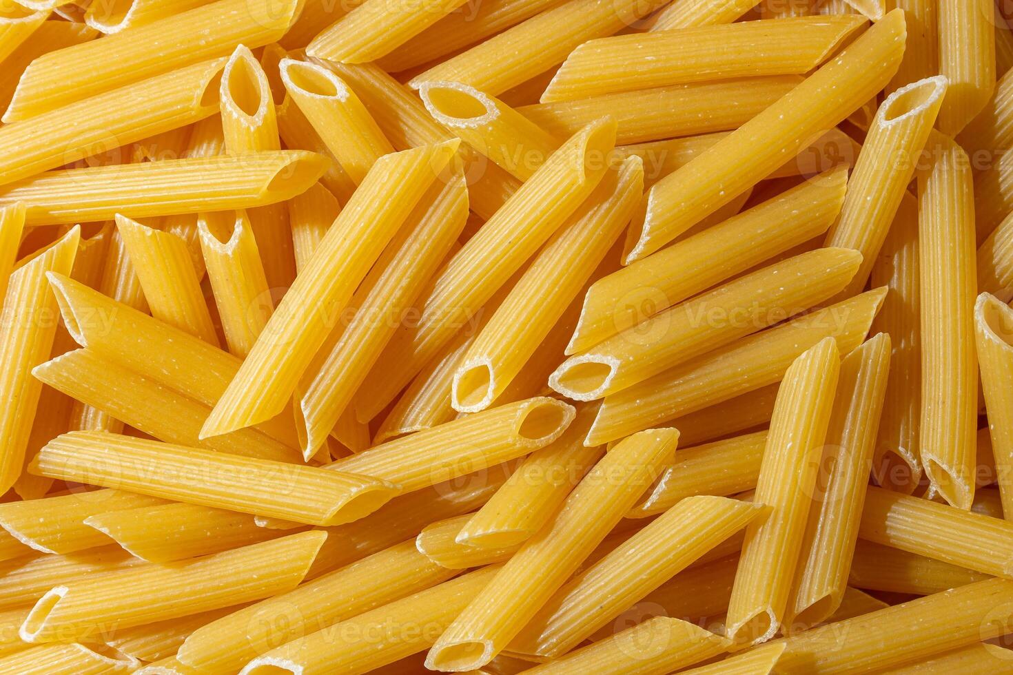 Uncooked Penne Rigate Pasta. A Culinary Canvas of Penne Macaroni, Creating a Lively and Textured Background for Gourmet Cooking. Dry Pasta. Raw Macaroni - Top View, Flat Lay photo