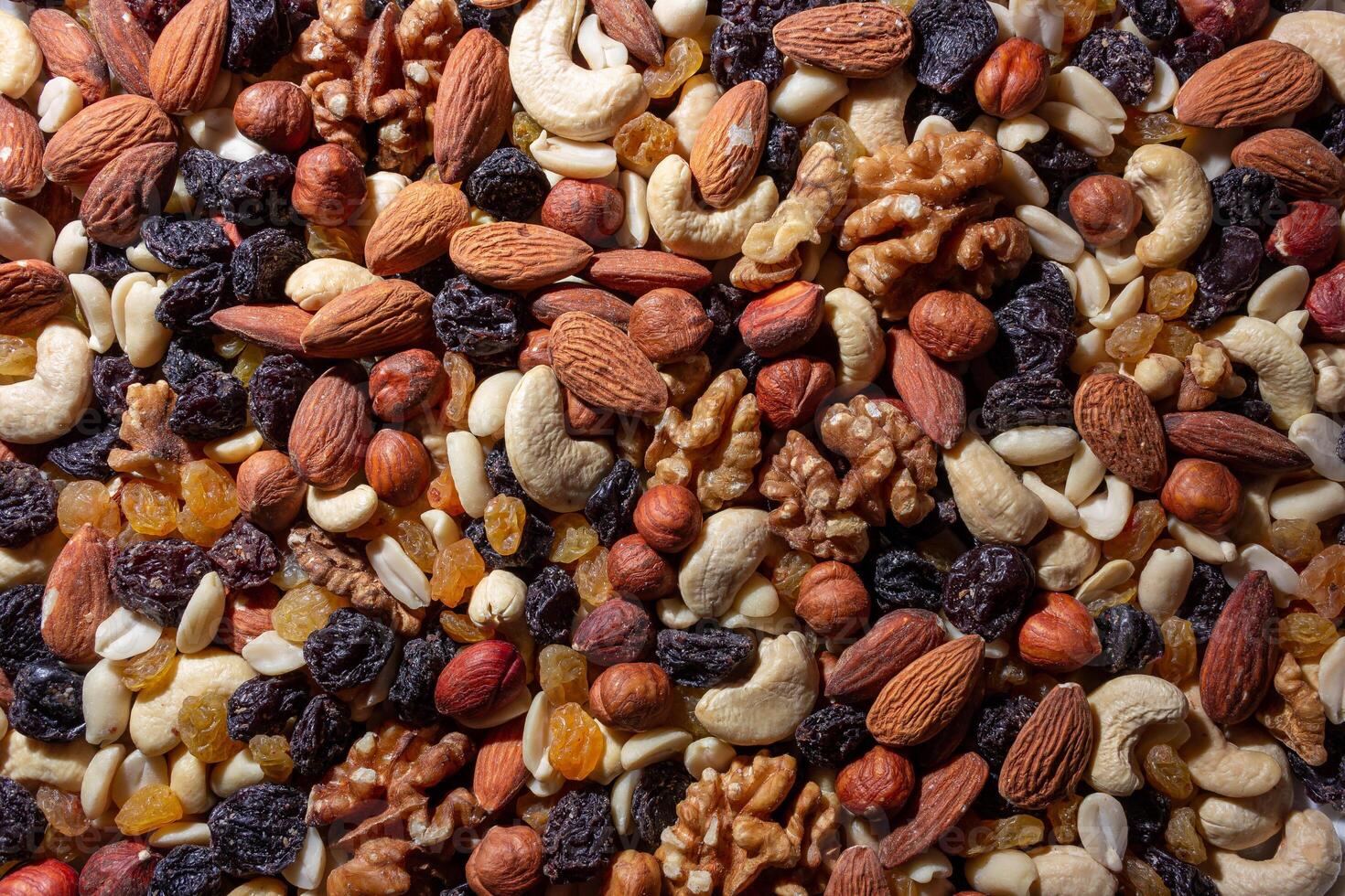 Mixed Nuts. Almonds, Walnuts, Cashews, Peanuts, Hazelnuts, Dried Prunes and Raisins. Different Nut Mix. Background from Various Nuts and Dried Fruits photo