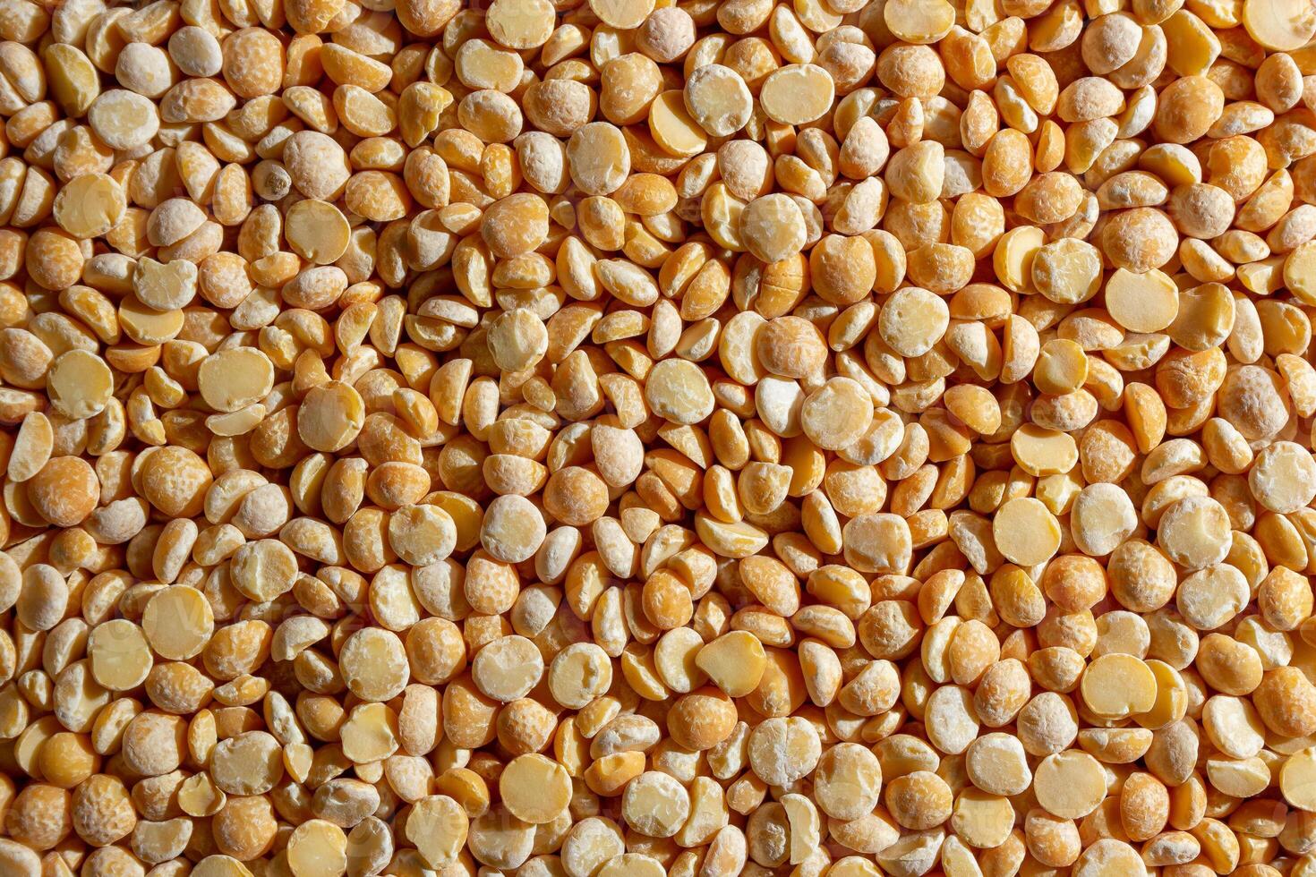 Uncooked Polished Split Peas Background. A Culinary Canvas of Dry Yellow Peas, Creating a Lively and Textured Background for Gourmet Cooking. Scattered Raw Polished Peas. Healthy Eating Ingredients photo