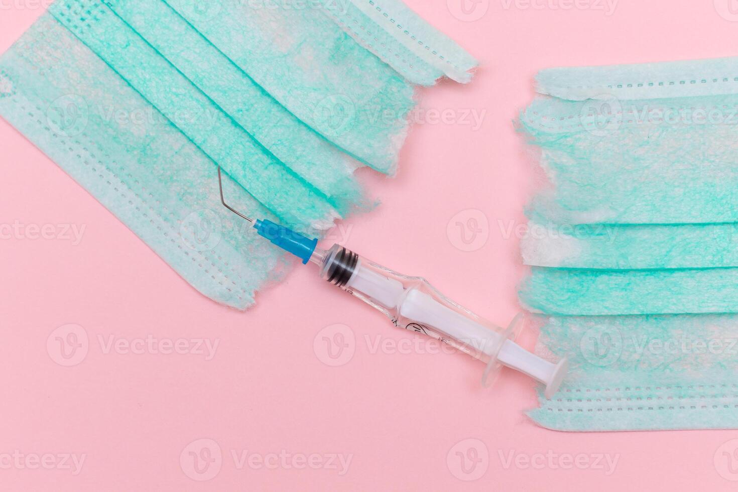 Anti Vaccine Movement and Anti Mask Concept - Broken Medical Syringe and Green Torn Medical Face Mask on the Pink Background. Pandemic and Lockdown End - Top View, Flat Lay photo