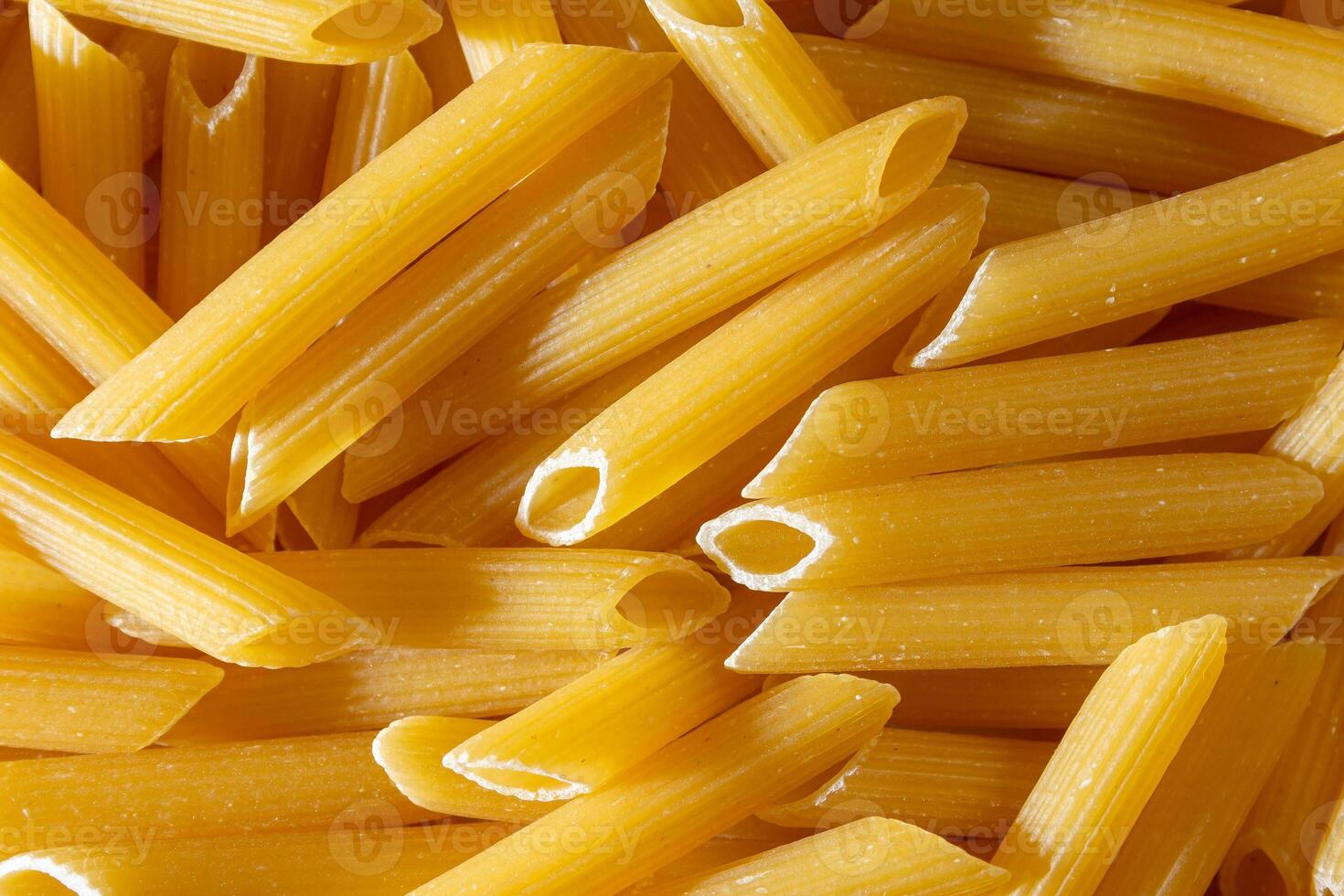 Uncooked Penne Rigate Pasta. A Culinary Canvas of Penne Macaroni, Creating a Lively and Textured Background for Gourmet Cooking. Dry Pasta. Raw Macaroni - Top View, Flat Lay photo