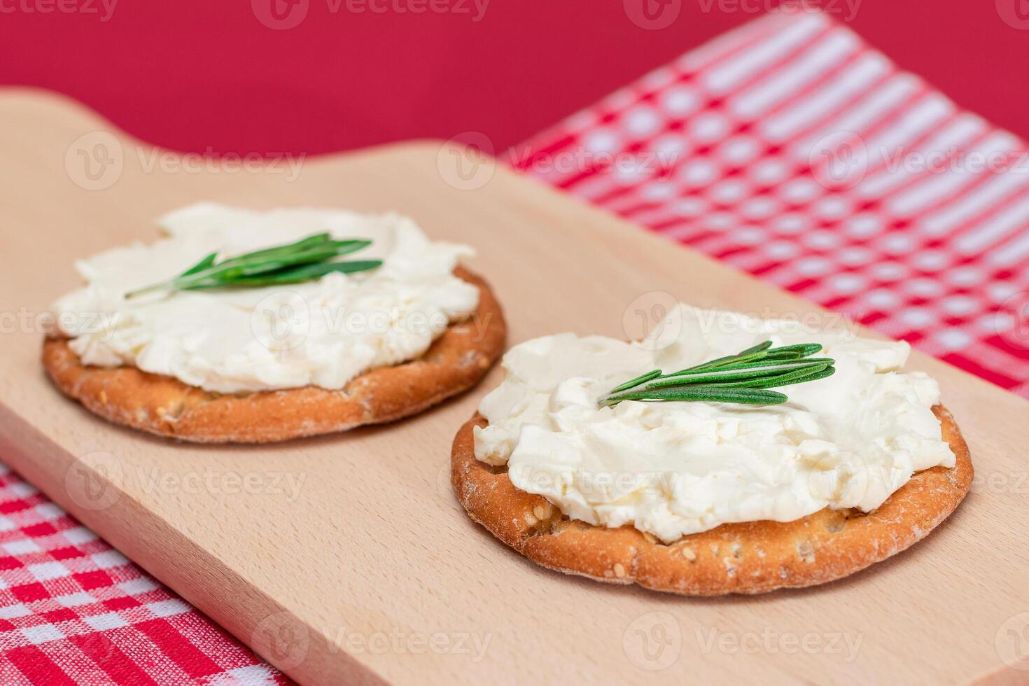 Crispy Cracker Sandwich with Cream Cheese and Rosemary on Wooden Cooking Board on Magenta Background photo