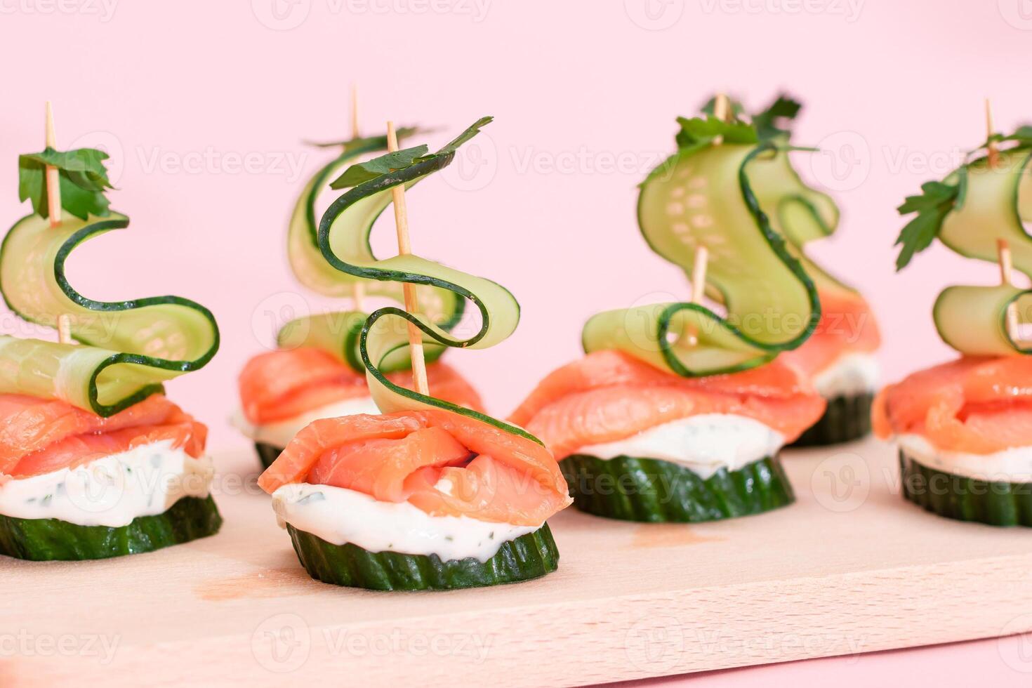 Canapes without Bread with Fresh Salmon, Cucumber and Cream Cheese on Wooden Cutting Board. Easy Breakfast. Diet Food. Quick and Healthy Sandwiches. Healthy Snacks with Tasty Fillings photo
