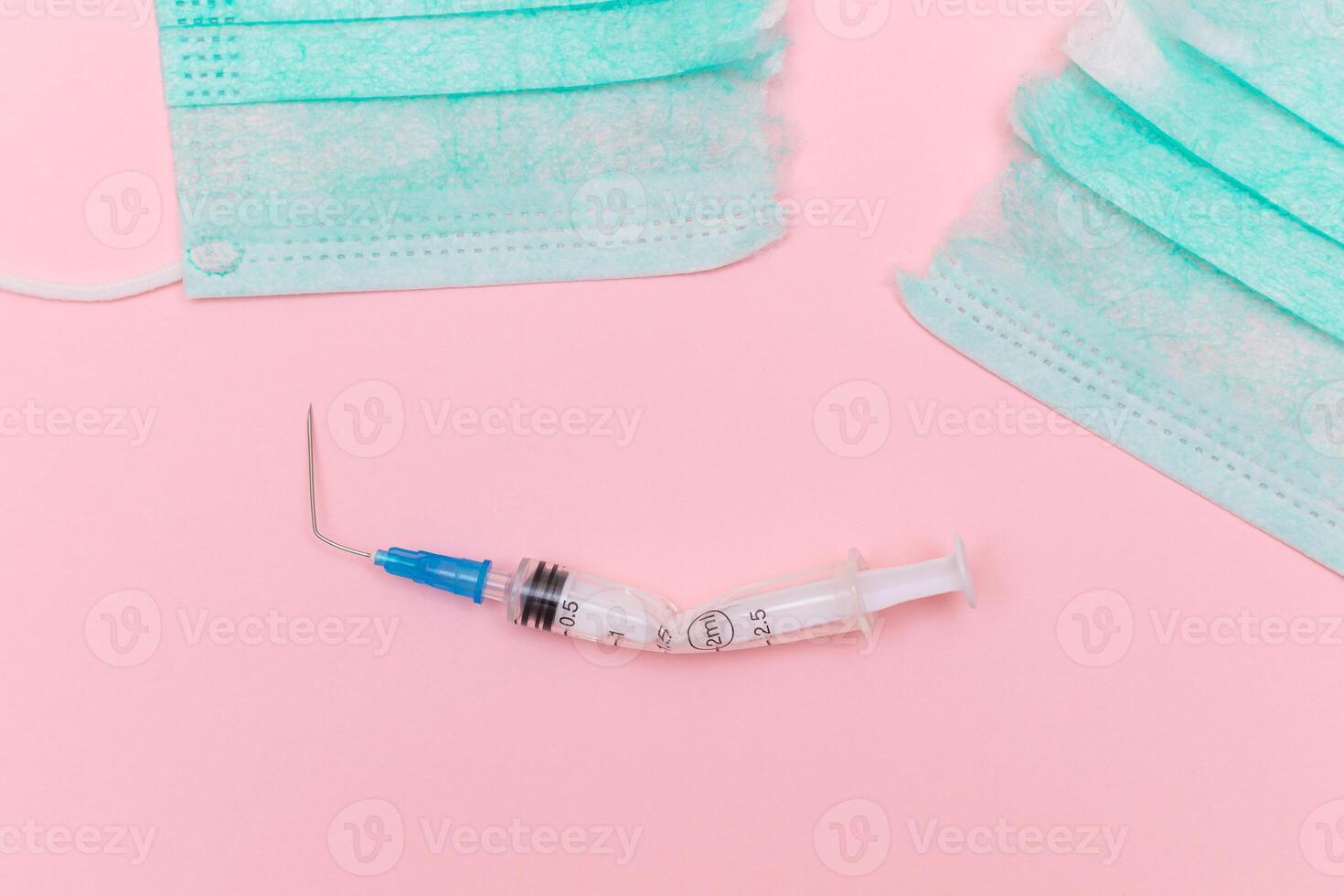 Anti Vaccine Movement and Anti Mask Concept - Broken Medical Syringe and Green Torn Medical Face Mask on the Pink Background. Pandemic and Lockdown End - Top View, Flat Lay photo