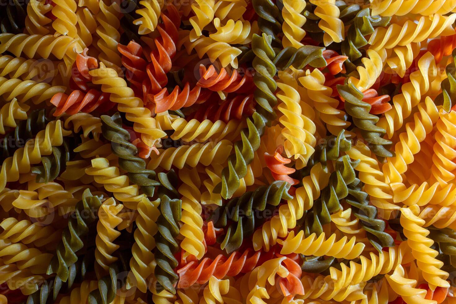 Uncooked Vibrant Colored Fusilli Pasta. A Mesmerizing Culinary Canvas of Multicolored Spirals, Creating a Lively and Textured Background for Gourmet Cooking. Colored Dry Pasta. Raw Macaroni photo