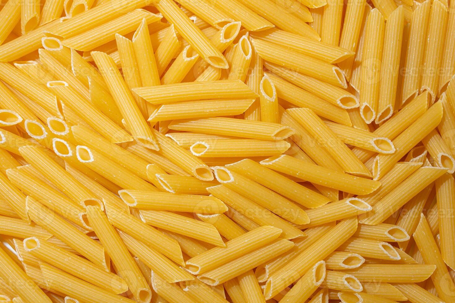 Uncooked Penne Rigate Pasta. A Culinary Canvas of Penne Macaroni, Creating a Lively and Textured Background for Gourmet Cooking. Dry Pasta. Raw Macaroni - Top View, Flat Lay photo