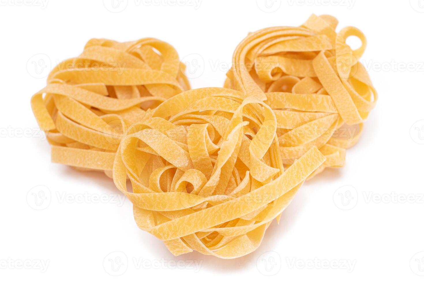 Three Classic Italian Raw Egg Fettuccine - Isolated on White Background. Dry Twisted Uncooked Pasta. Italian Culture and Cuisine. Raw Golden Macaroni Pattern - Isolation photo