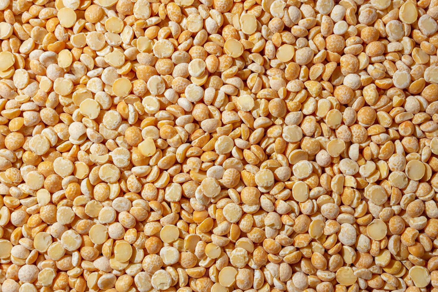 Uncooked Polished Split Peas Background. A Culinary Canvas of Dry Yellow Peas, Creating a Lively and Textured Background for Gourmet Cooking. Scattered Raw Polished Peas. Healthy Eating Ingredients photo