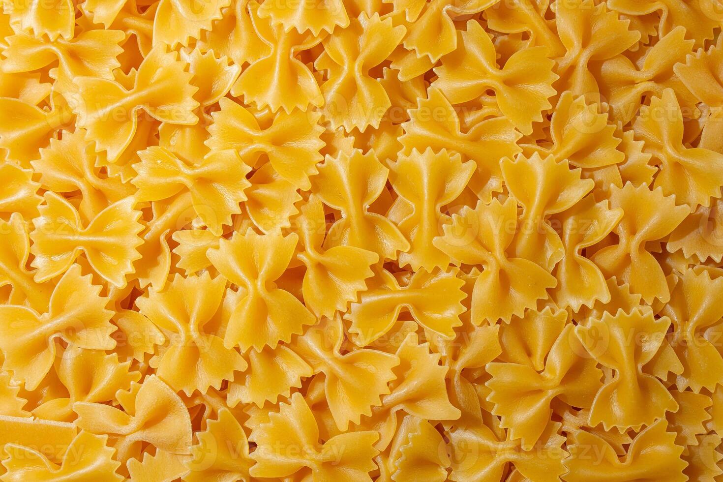 Uncooked Farfalle Pasta. A Culinary Canvas of Bow-Tie Macaroni, Creating a Lively and Textured Background for Gourmet Cooking. Dry Pasta. Raw Macaroni - Top View, Flat Lay photo
