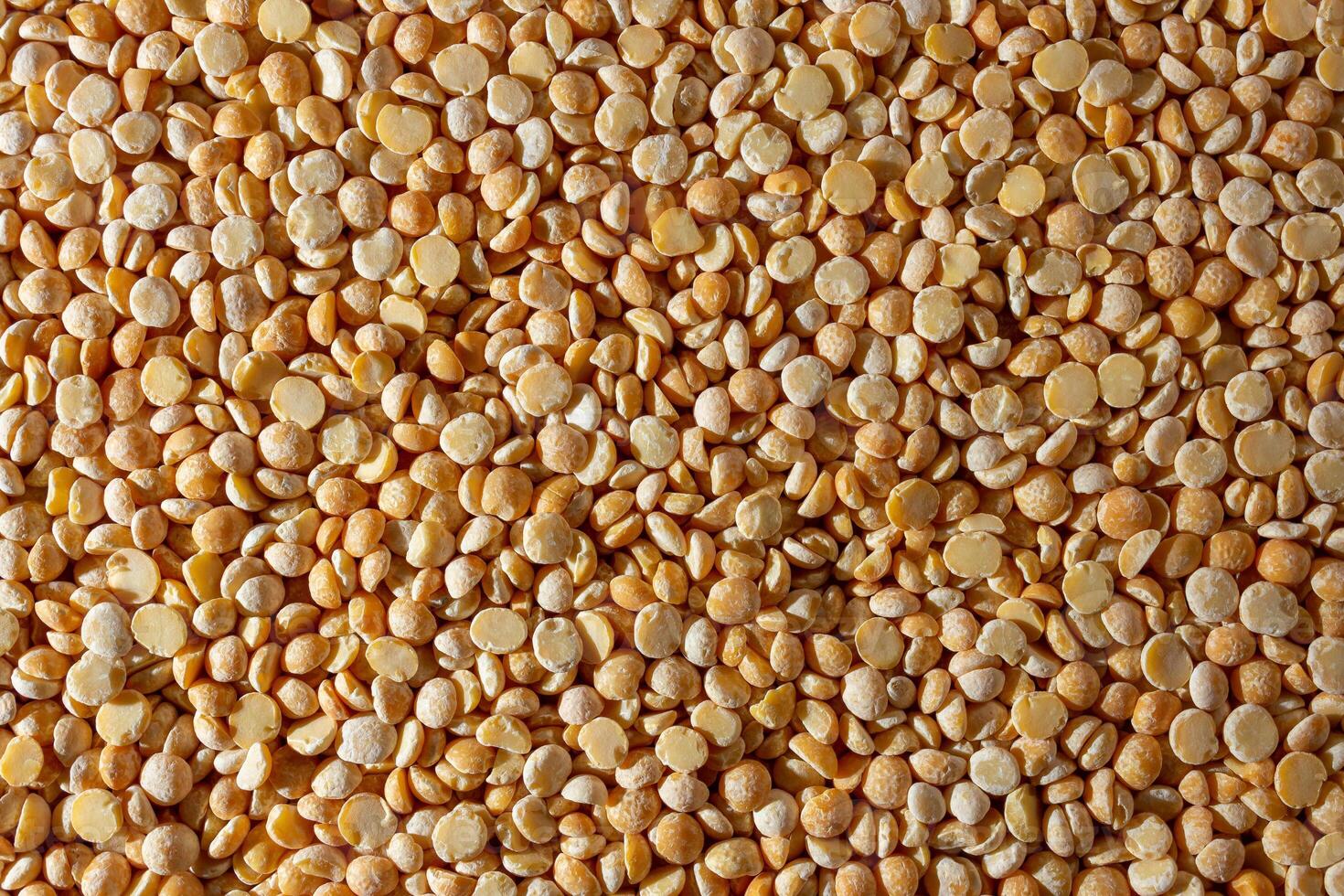 Uncooked Polished Split Peas Background. A Culinary Canvas of Dry Yellow Peas, Creating a Lively and Textured Background for Gourmet Cooking. Scattered Raw Polished Peas. Healthy Eating Ingredients photo