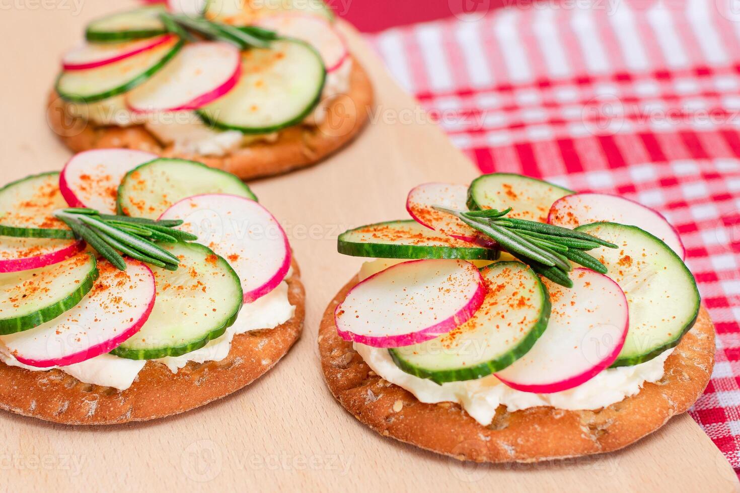 Light Breakfast or Diet Eating - Crispy Cracker Sandwich with Cream Cheese, Fresh Cucumber and Radish on Wooden Cooking Board on Magenta Background photo