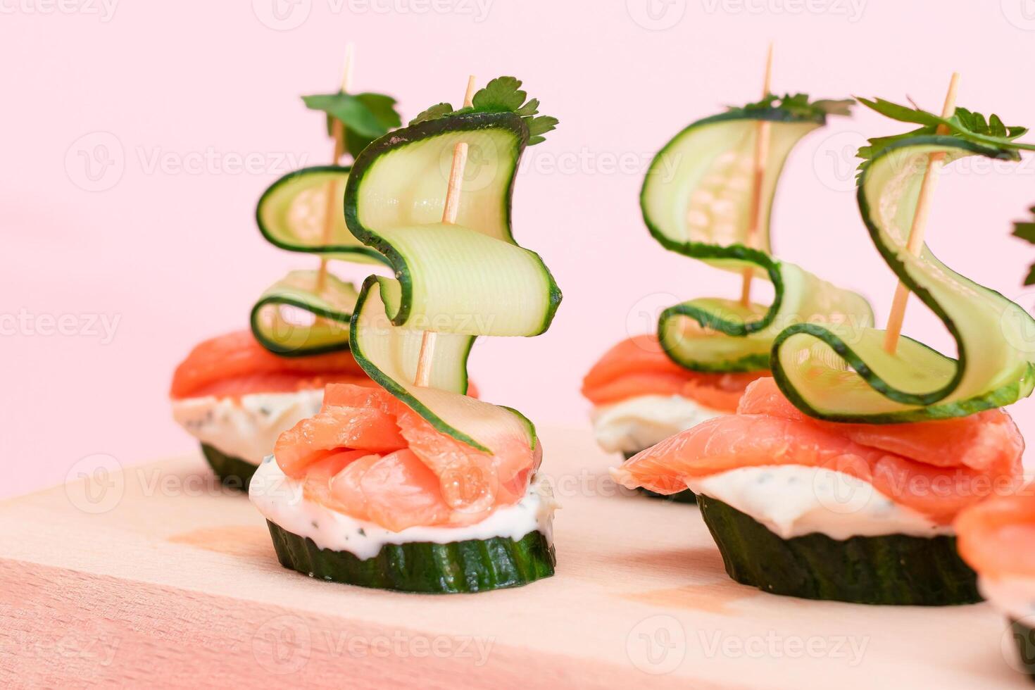 Canapes without Bread with Fresh Salmon, Cucumber and Cream Cheese on Wooden Cutting Board. Easy Breakfast. Diet Food. Quick and Healthy Sandwiches. Healthy Snacks with Tasty Fillings photo