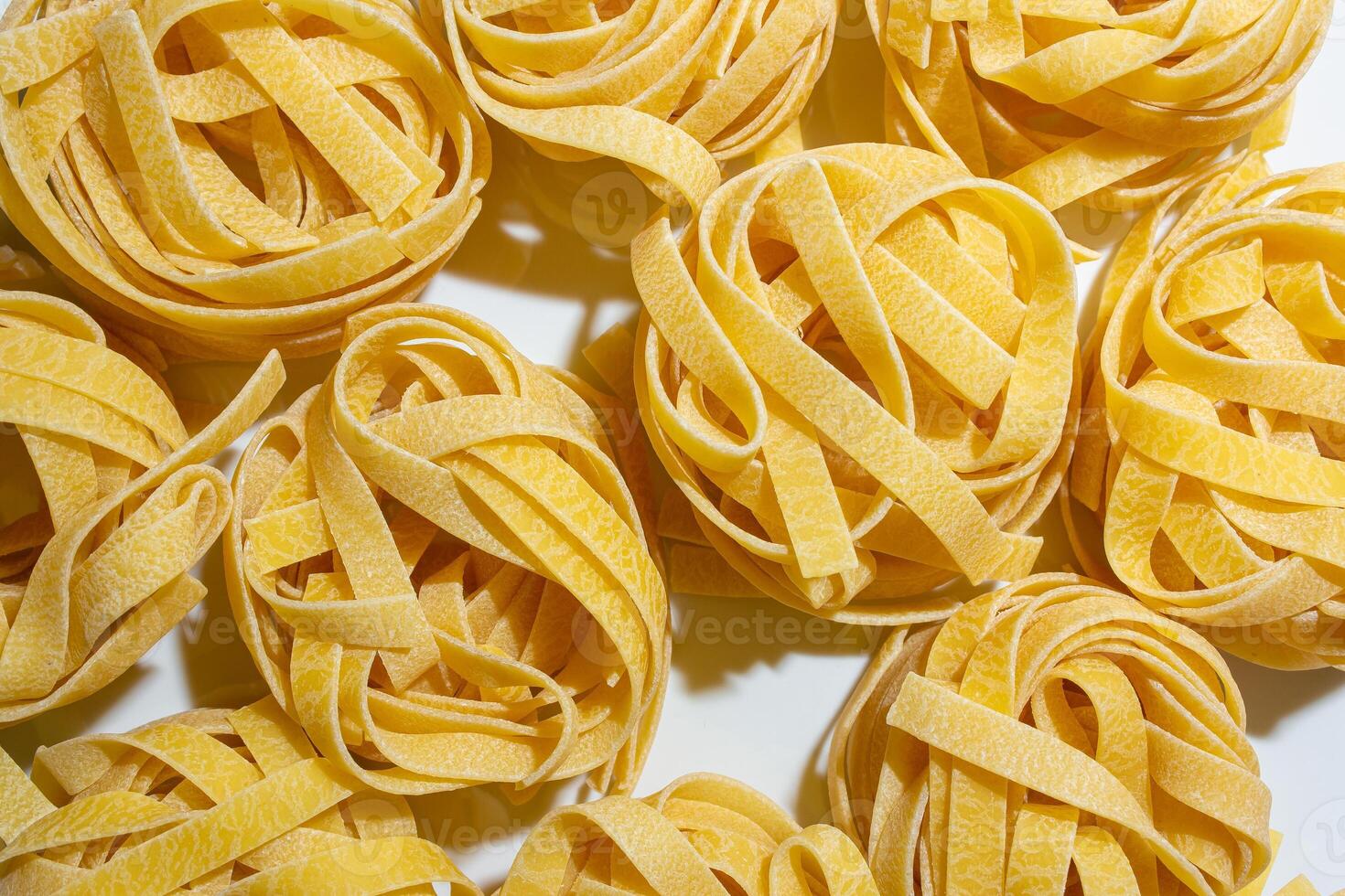 Uncooked Egg-Based Fettuccine Pasta. A Culinary Canvas of Ribbon-Shaped Macaroni, Creating a Lively and Textured Background for Gourmet Cooking. Dry Pasta. Raw Macaroni - Top View, Flat Lay photo