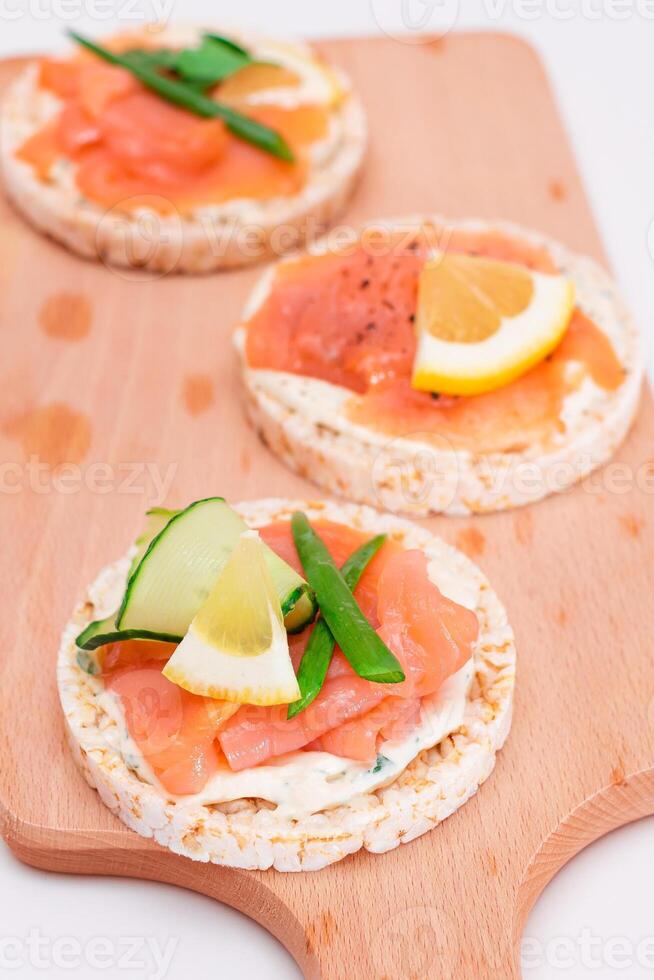 Rice Cake Sandwiches with Fresh Salmon, Cucumber, Lemon and Greens on Wooden Cutting Board. Diet Food. Quick and Healthy Sandwiches. Crispbread with Fresh Fillings. Healthy Dietary Snacks photo