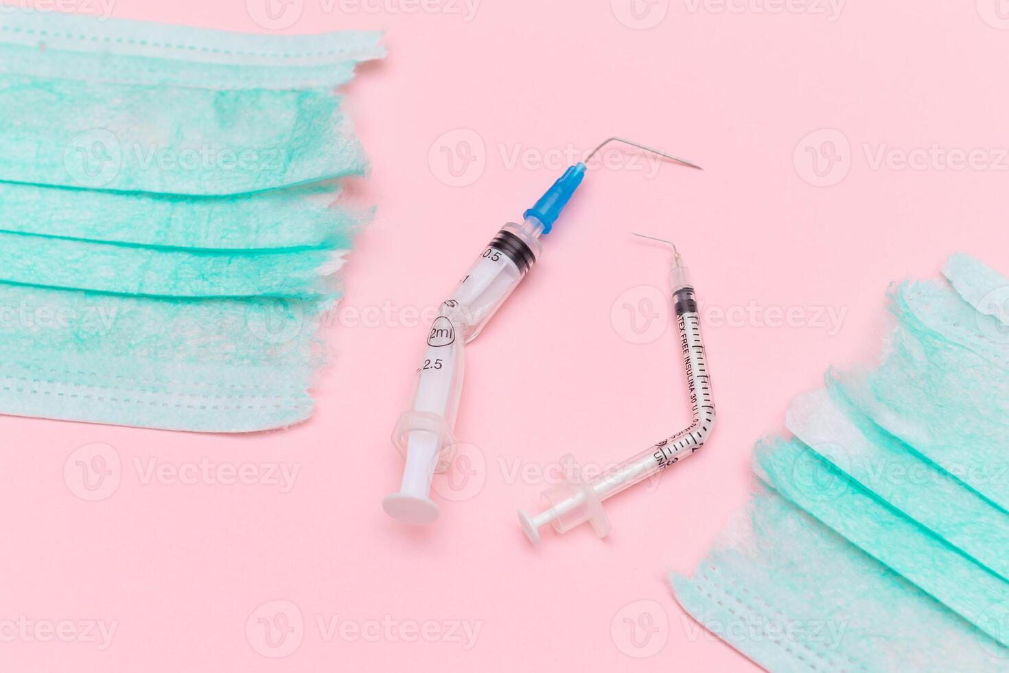 Anti Vaccine Movement and Anti Mask Concept - Broken Medical Syringe and Green Torn Medical Face Mask on the Pink Background. Pandemic and Lockdown End - Top View, Flat Lay photo