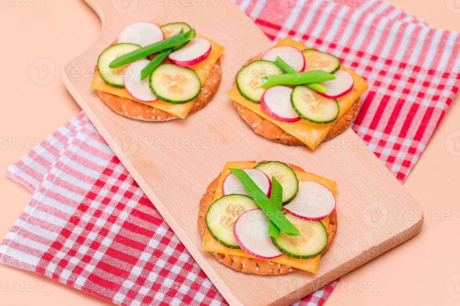Light Breakfast. Quick and Healthy Sandwich. Fresh Cucumber and Radish with Green Onions and Cheese on Crispy Cracker on Wooden Cutting Board photo