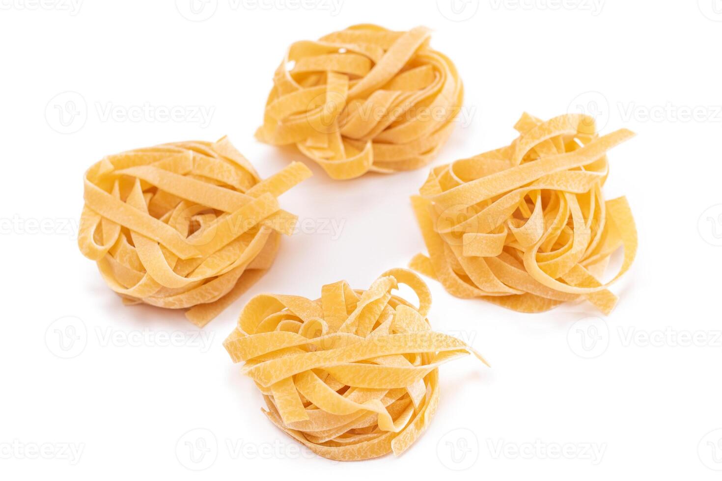 Four Classic Italian Raw Egg Fettuccine - Isolated on White Background. Dry Twisted Uncooked Pasta. Italian Culture and Cuisine. Raw Golden Macaroni Pattern - Isolation photo