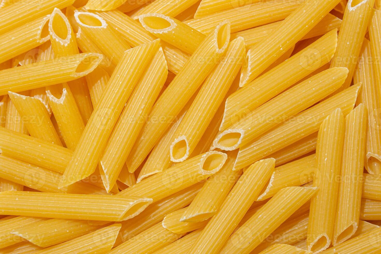 Uncooked Penne Rigate Pasta. A Culinary Canvas of Penne Macaroni, Creating a Lively and Textured Background for Gourmet Cooking. Dry Pasta. Raw Macaroni - Top View, Flat Lay photo