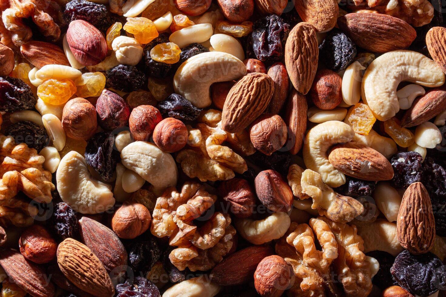 Mixed Nuts. Almonds, Walnuts, Cashews, Peanuts, Hazelnuts, Dried Prunes and Raisins. Different Nut Mix. Background from Various Nuts and Dried Fruits photo