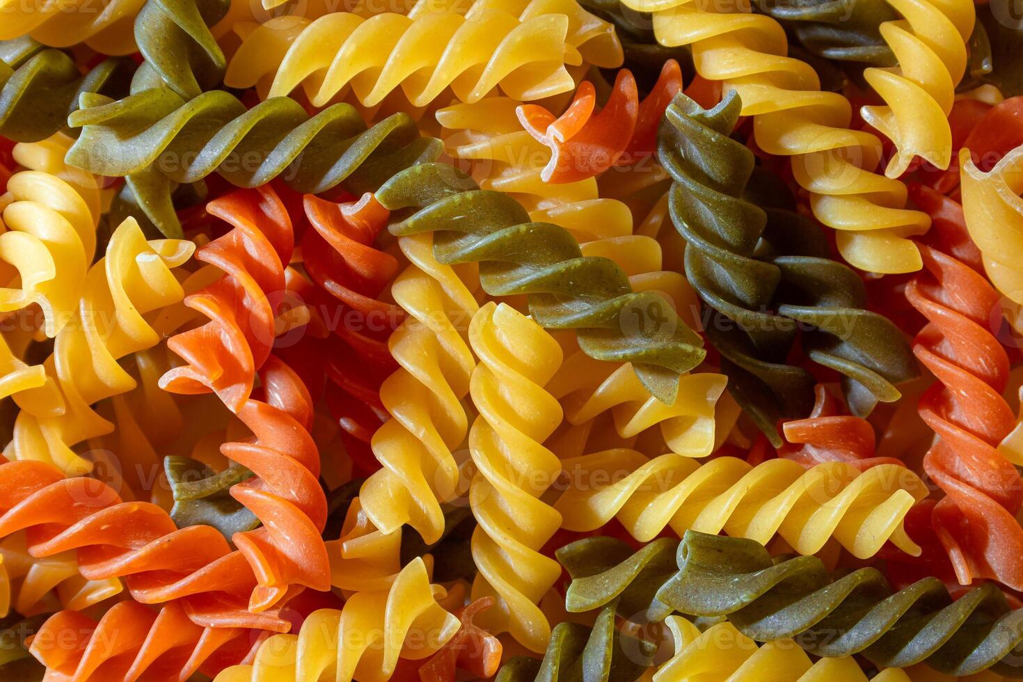 Uncooked Vibrant Colored Fusilli Pasta. A Mesmerizing Culinary Canvas of Multicolored Spirals, Creating a Lively and Textured Background for Gourmet Cooking. Colored Dry Pasta. Raw Macaroni photo