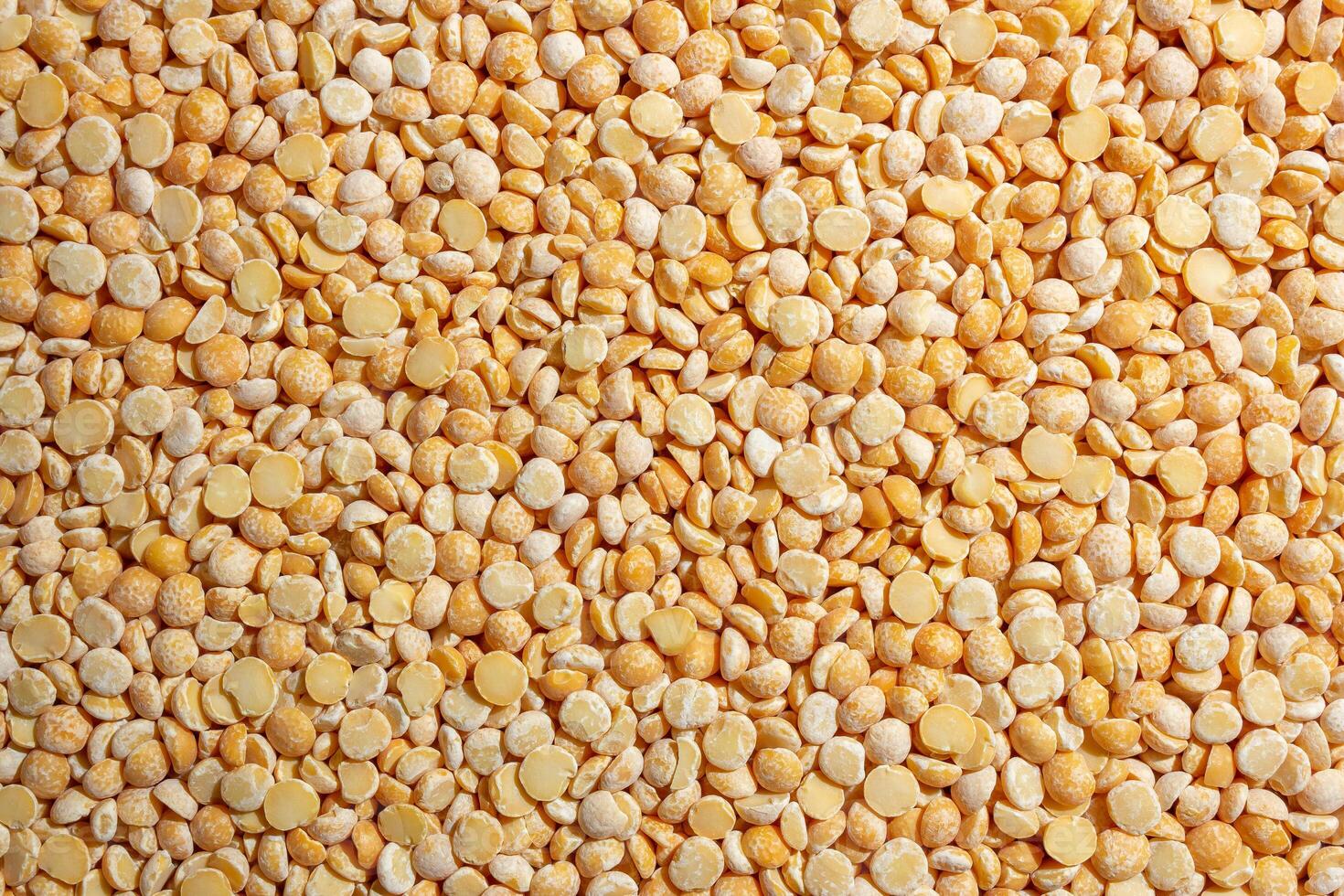 Uncooked Polished Split Peas Background. A Culinary Canvas of Dry Yellow Peas, Creating a Lively and Textured Background for Gourmet Cooking. Scattered Raw Polished Peas. Healthy Eating Ingredients photo